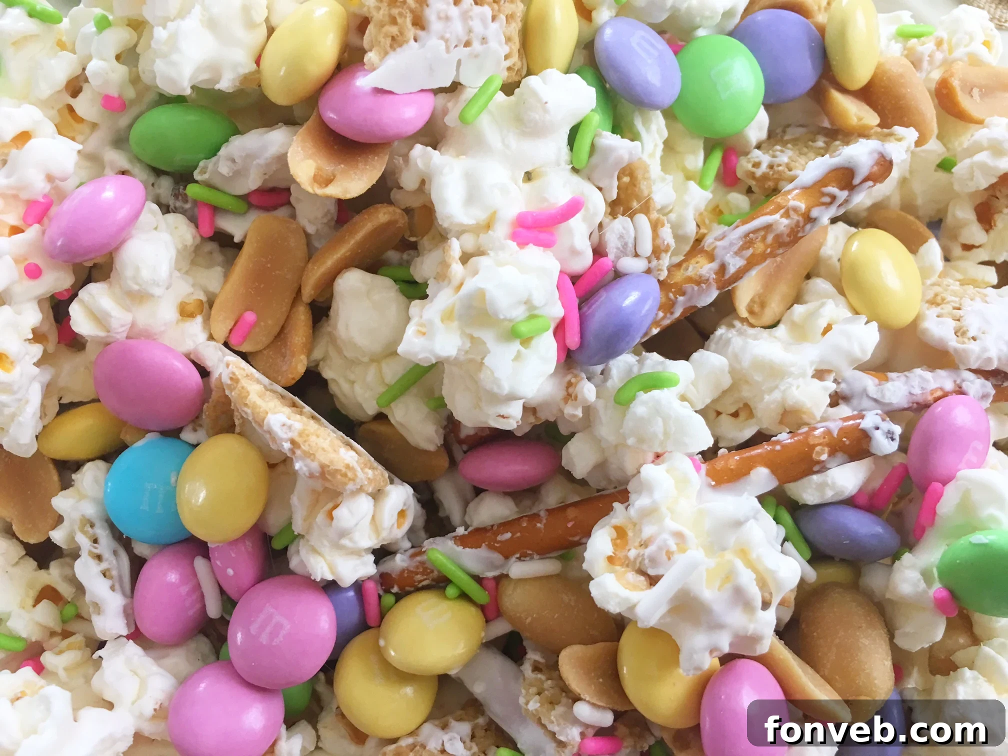 Close-up of Bunny Bait Easter Crack mix with colorful M&Ms, pretzels, and popcorn, topped with white chocolate drizzle
