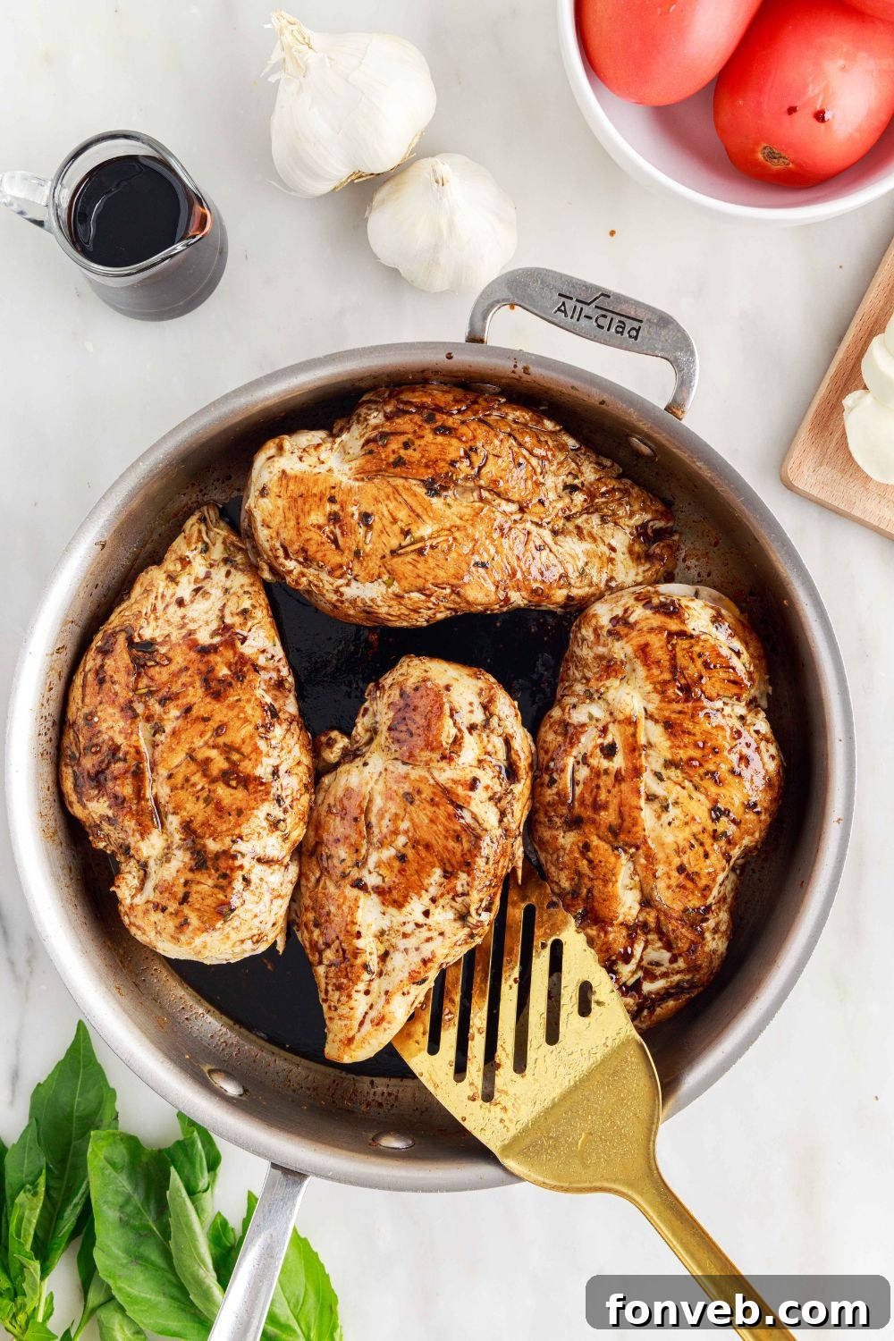Caprese Stuffed Chicken in a pan being flipped with a spatula to cook both sides evenly