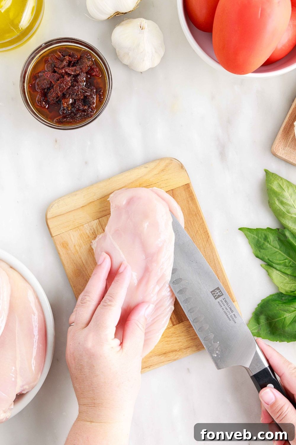 Raw chicken on a cutting board being butterfly cut, showing the initial incision