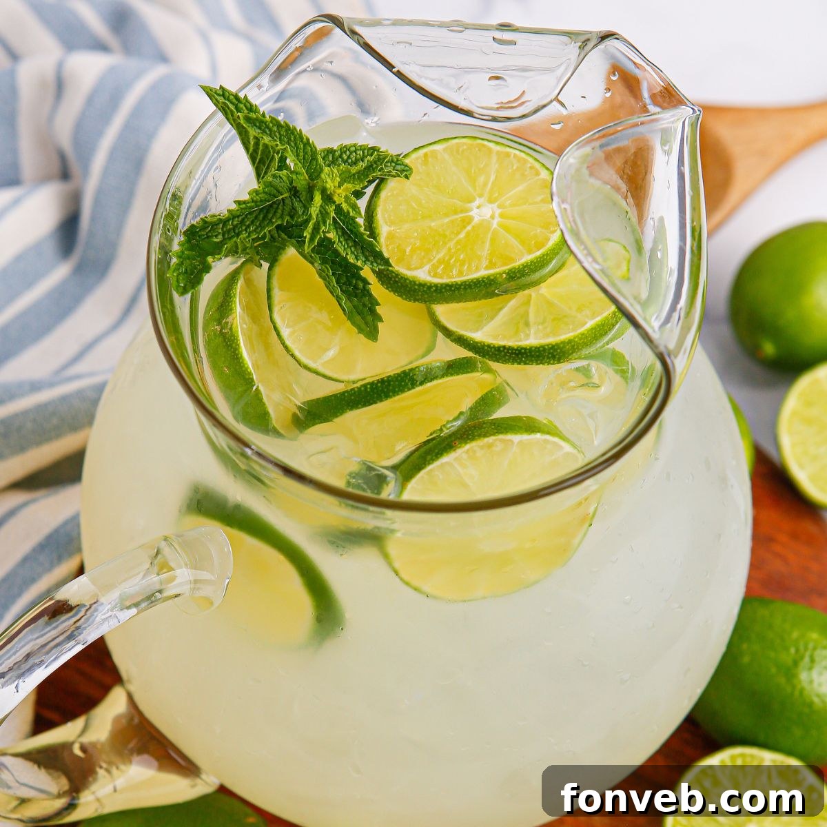 Limeade in a pitcher topped with sliced limes and mint leaves