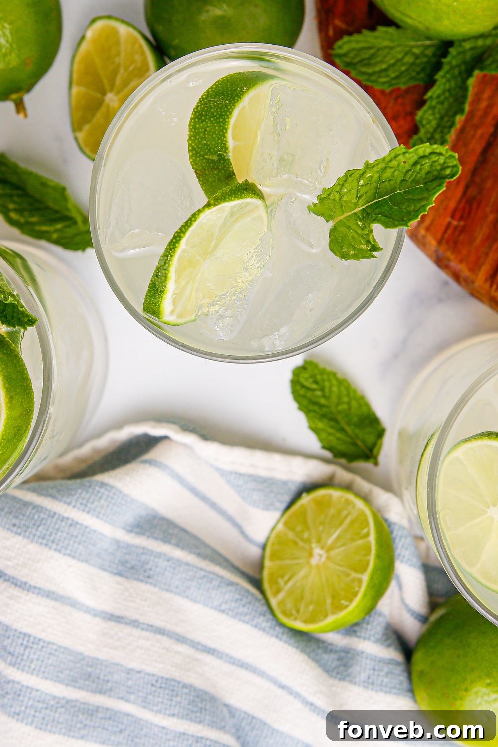 Limeade in glasses on table with a blue and white stripe on it sitting on table