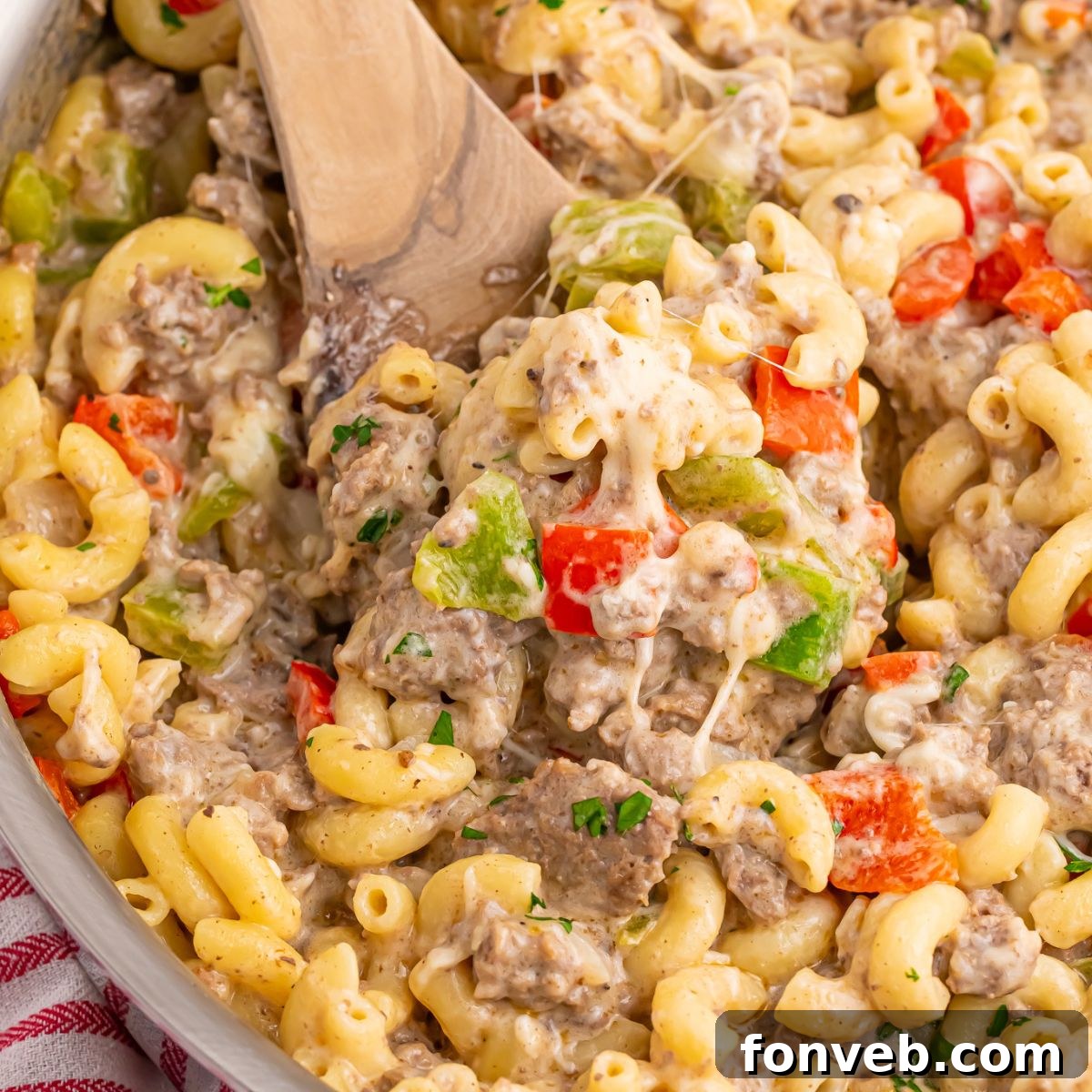 Creamy Philly Cheesesteak Pasta 2 Philly Cheesesteak Pasta in a pan with a wooden spatula with some of the mixture on it