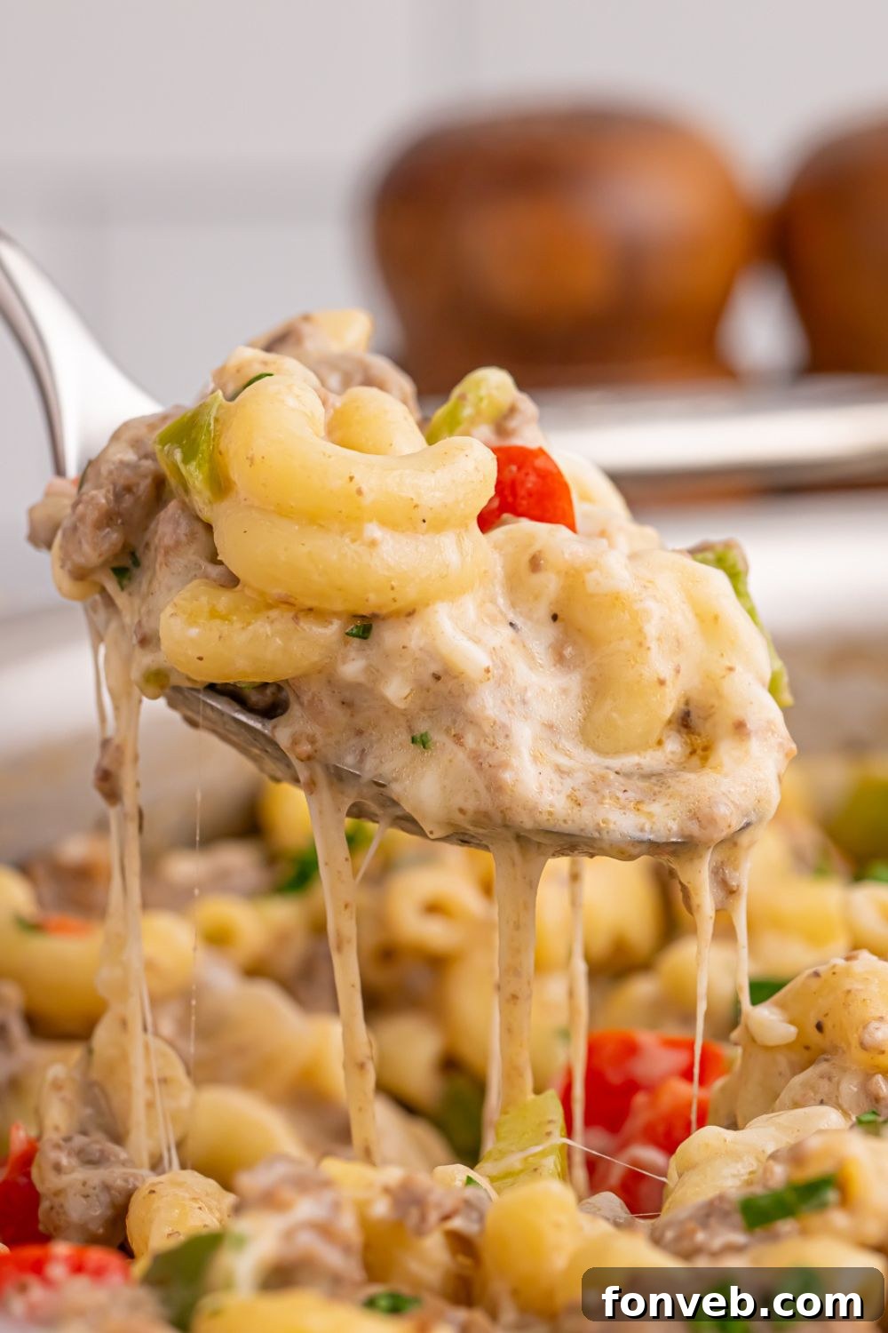 Creamy Philly Cheesesteak Pasta 14 spoon above pan full of Philly Cheesesteak Pasta