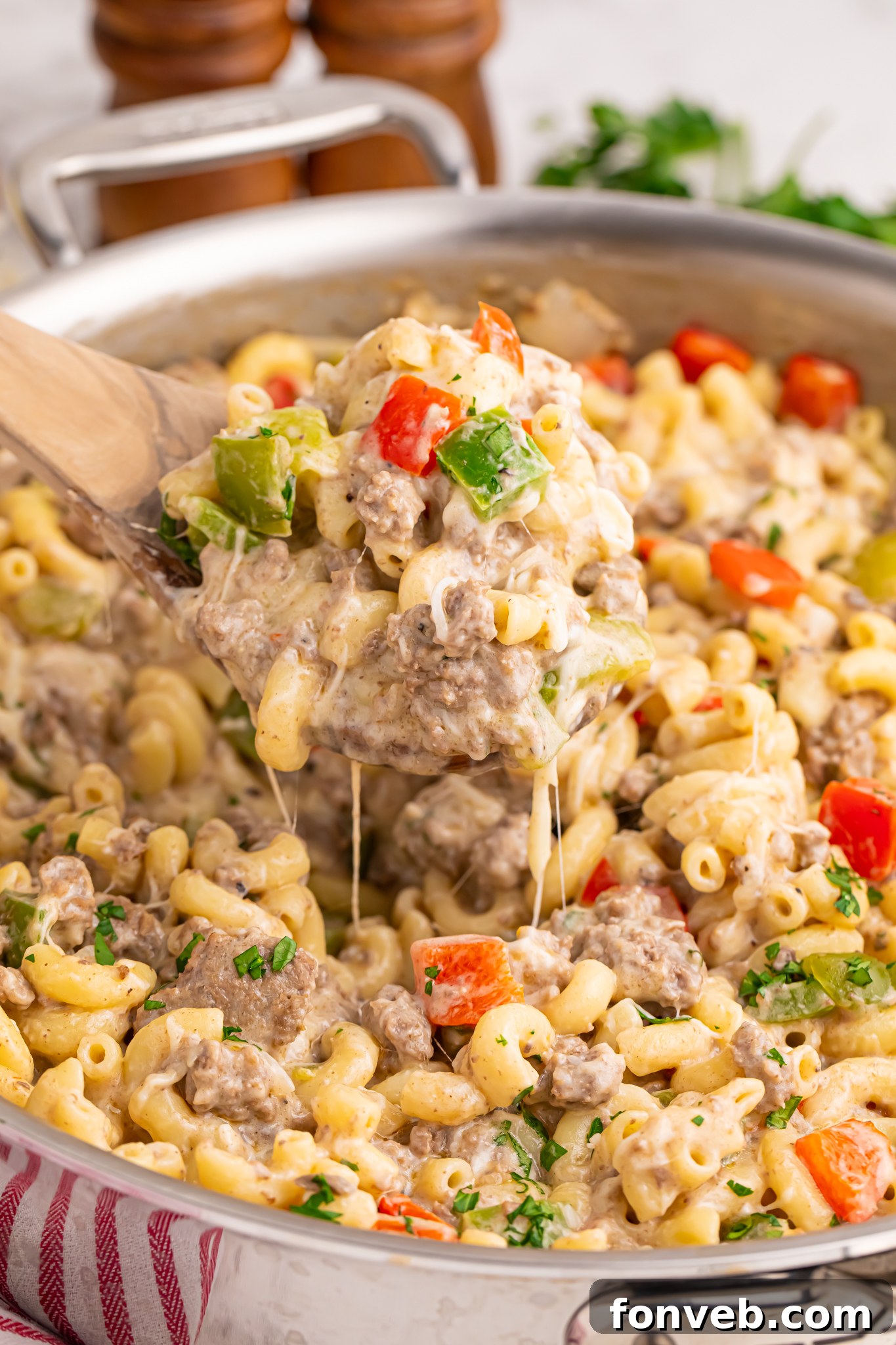 Creamy Philly Cheesesteak Pasta 18 Philly Cheesesteak Pasta in a skillet on table with spoon lifting up a large bite