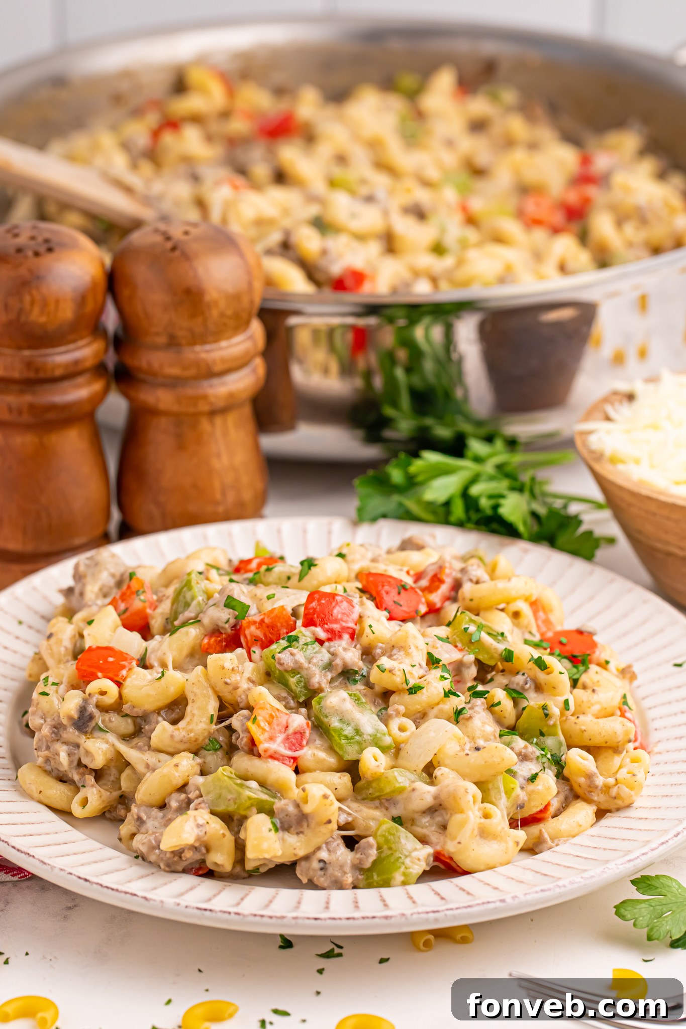Creamy Philly Cheesesteak Pasta 19 Philly Cheesesteak Pasta in a skillet in the background with a plate full in front