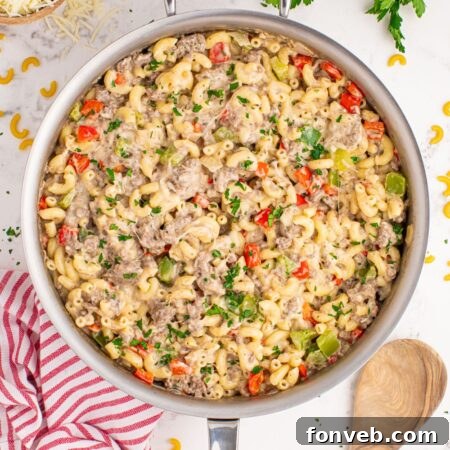 Philly Cheesesteak Pasta in a skillet on table with spoon beside pan