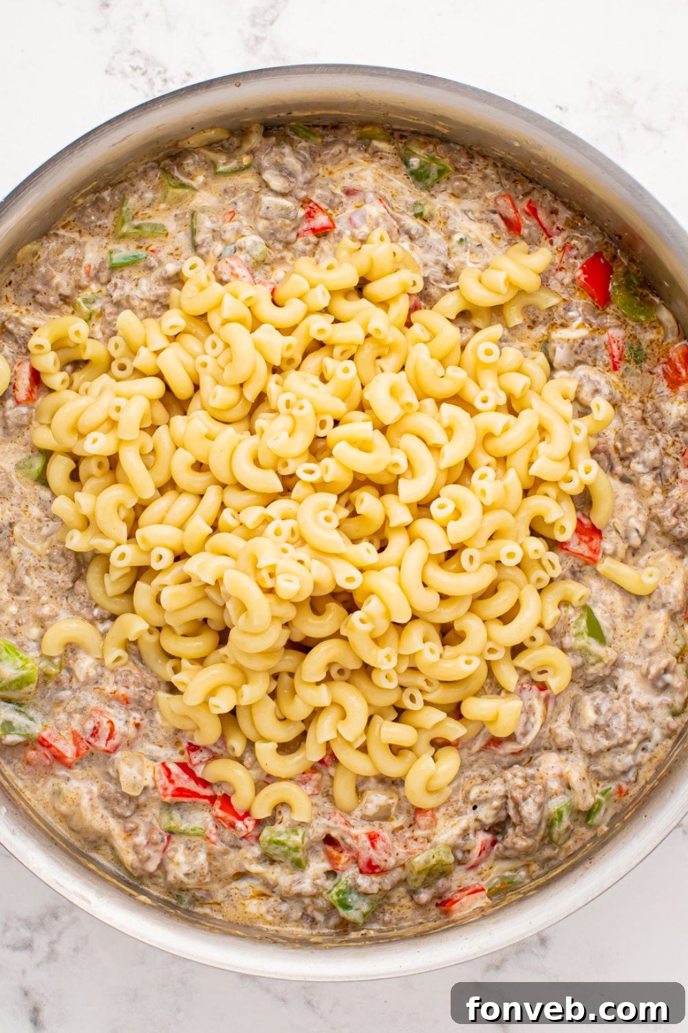 Creamy Philly Cheesesteak Pasta 8 Philly Cheesesteak Pasta mixture in a pan with cooked pasta poured on top of the meat mixture