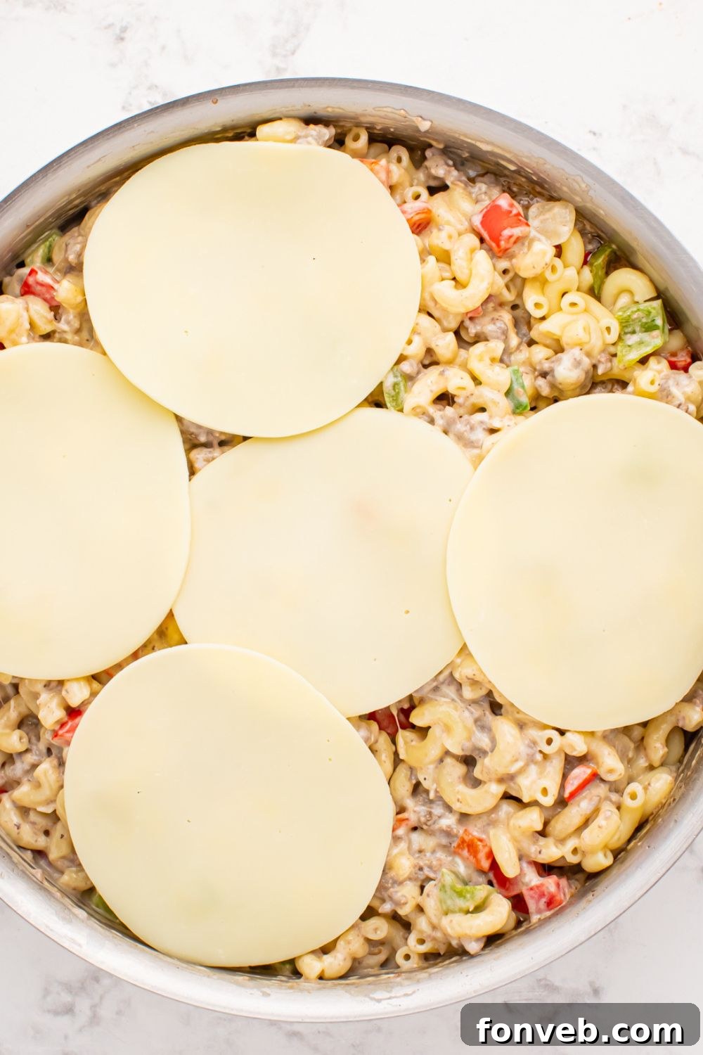 Creamy Philly Cheesesteak Pasta 9 provolone cheese slices on top of the Philly Cheesesteak Pasta mixture in skillet