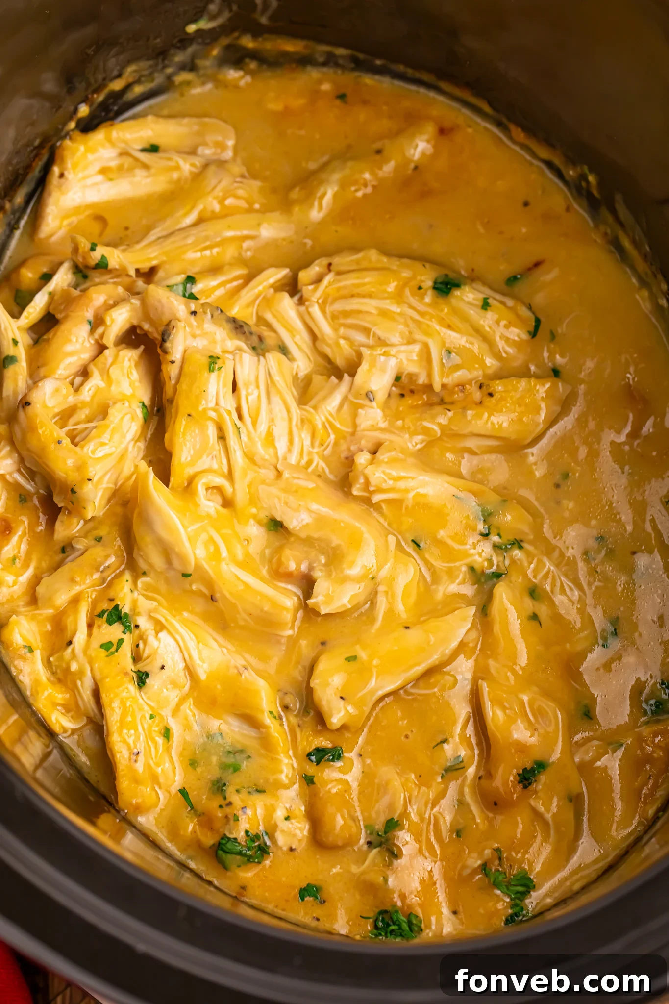 overhead look of shredded chicken and gravy in a slow cooker