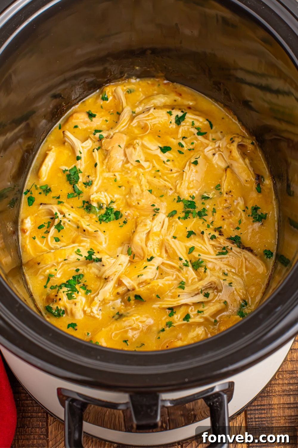 overhead look of crockpot with chicken and gravy in the pot with parsley sprinkled on top