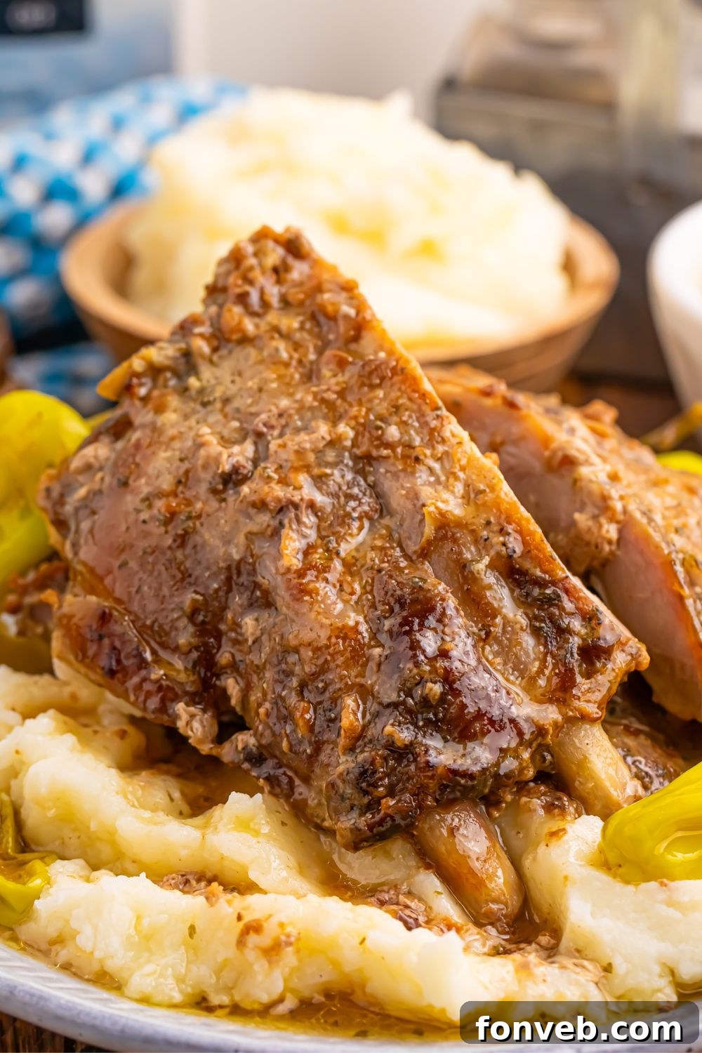 Mississippi ribs on top of a bed of potatoes and peppercini peppers on plate