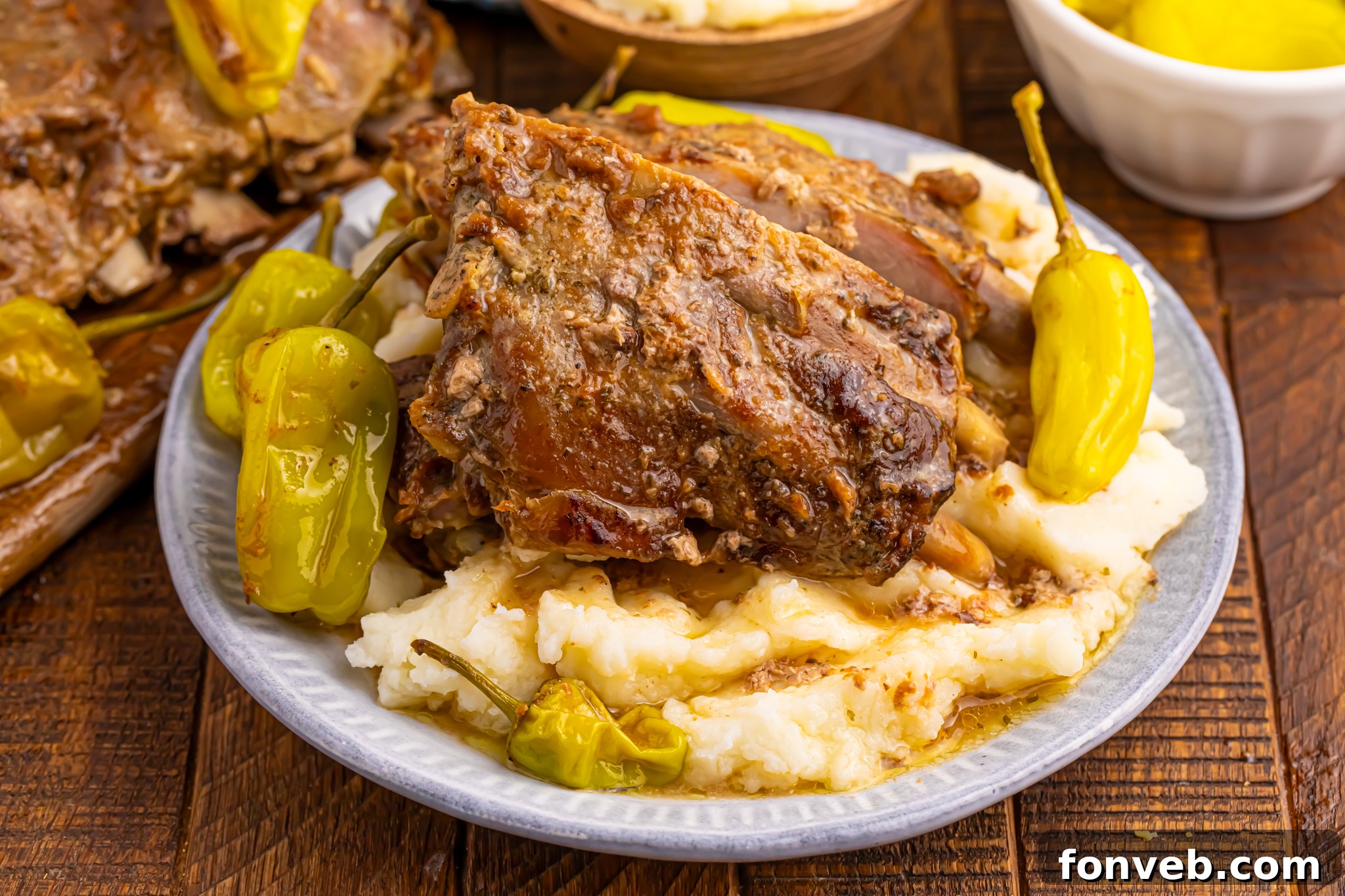 Slow Cooker Mississippi Ribs on a white plate smothered in gravy sitting on top of mashed potatoes