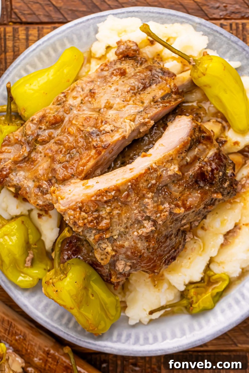 plate of baby back ribs, potatoes, and peppers sitting on wooden table
