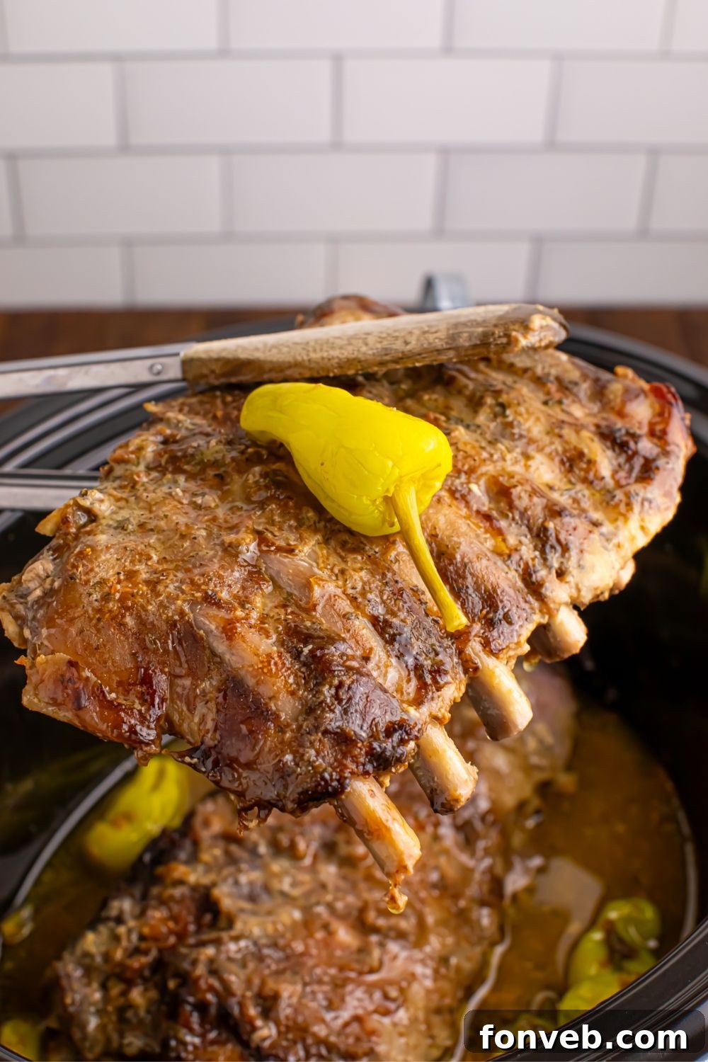 baby back ribs being held with tong above the slow cooker sitting on the table