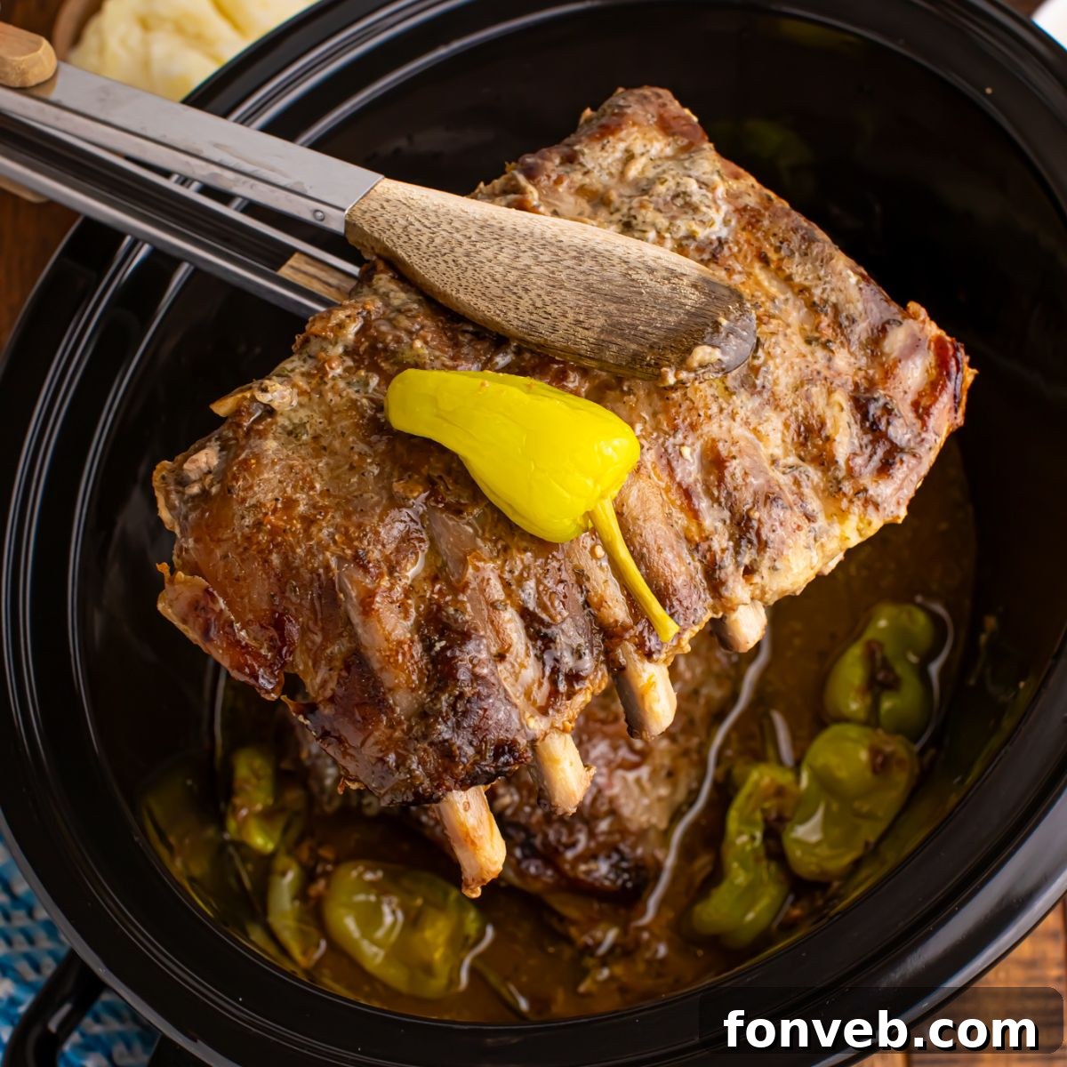 Slow Cooker Mississippi Ribs in crockpot with a rib section being lifted out of crockpot with tongs