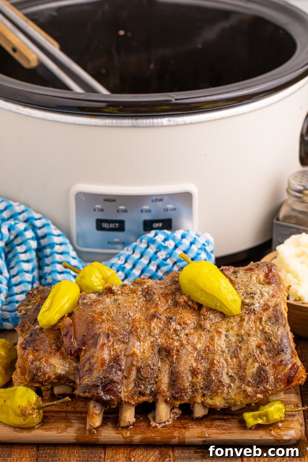 Mississippi Ribs on wooden cutting board with crockpot in the background
