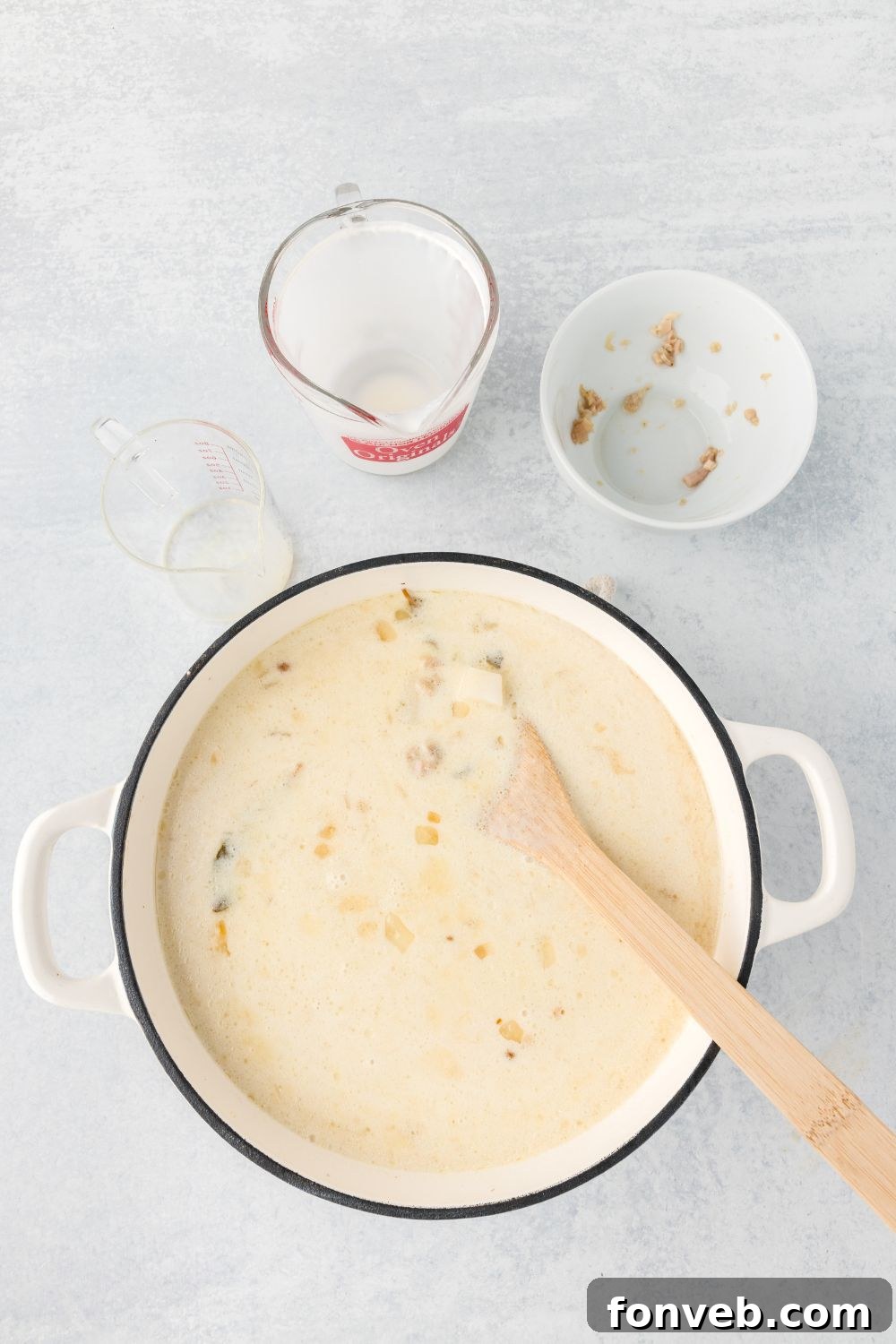 stirring the heavy cream into the pot of New England Clam Chowder