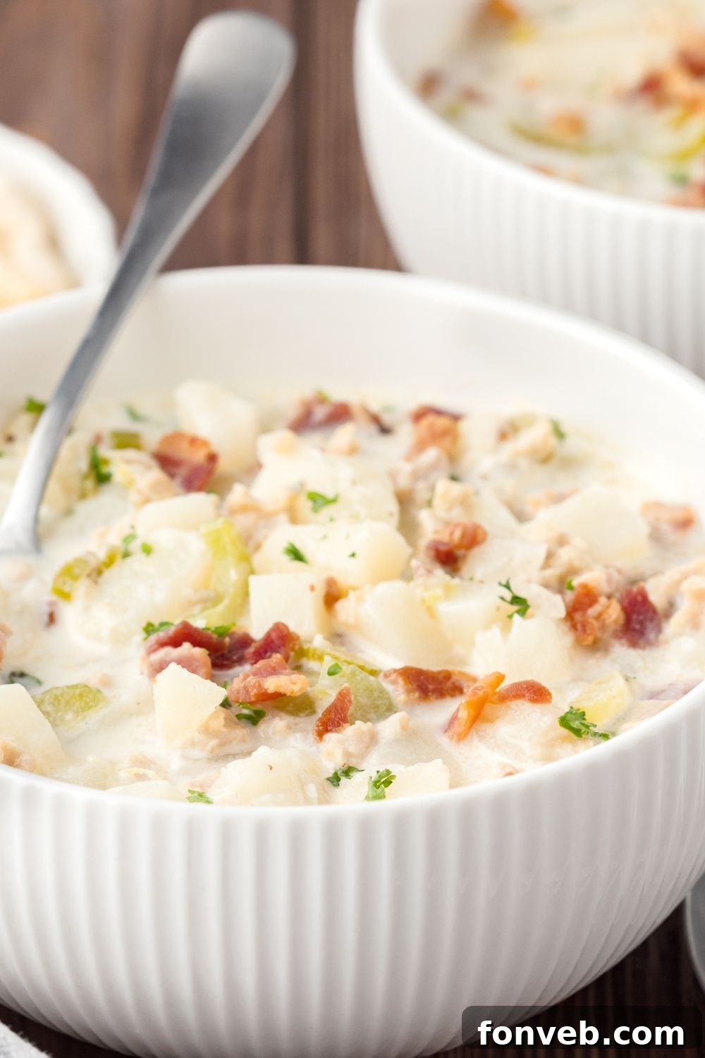 bowls of clam chowder on table with a spoon sitting in the bowl
