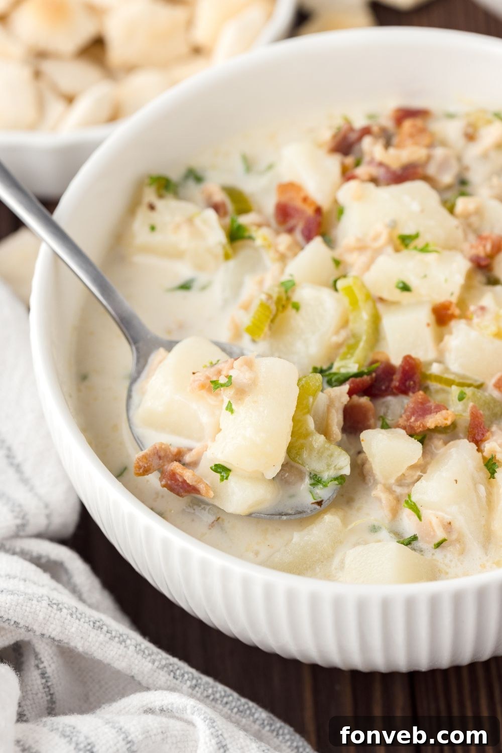 New England Clam Chowder in a white bowl with a spoonful of soup in bowl 