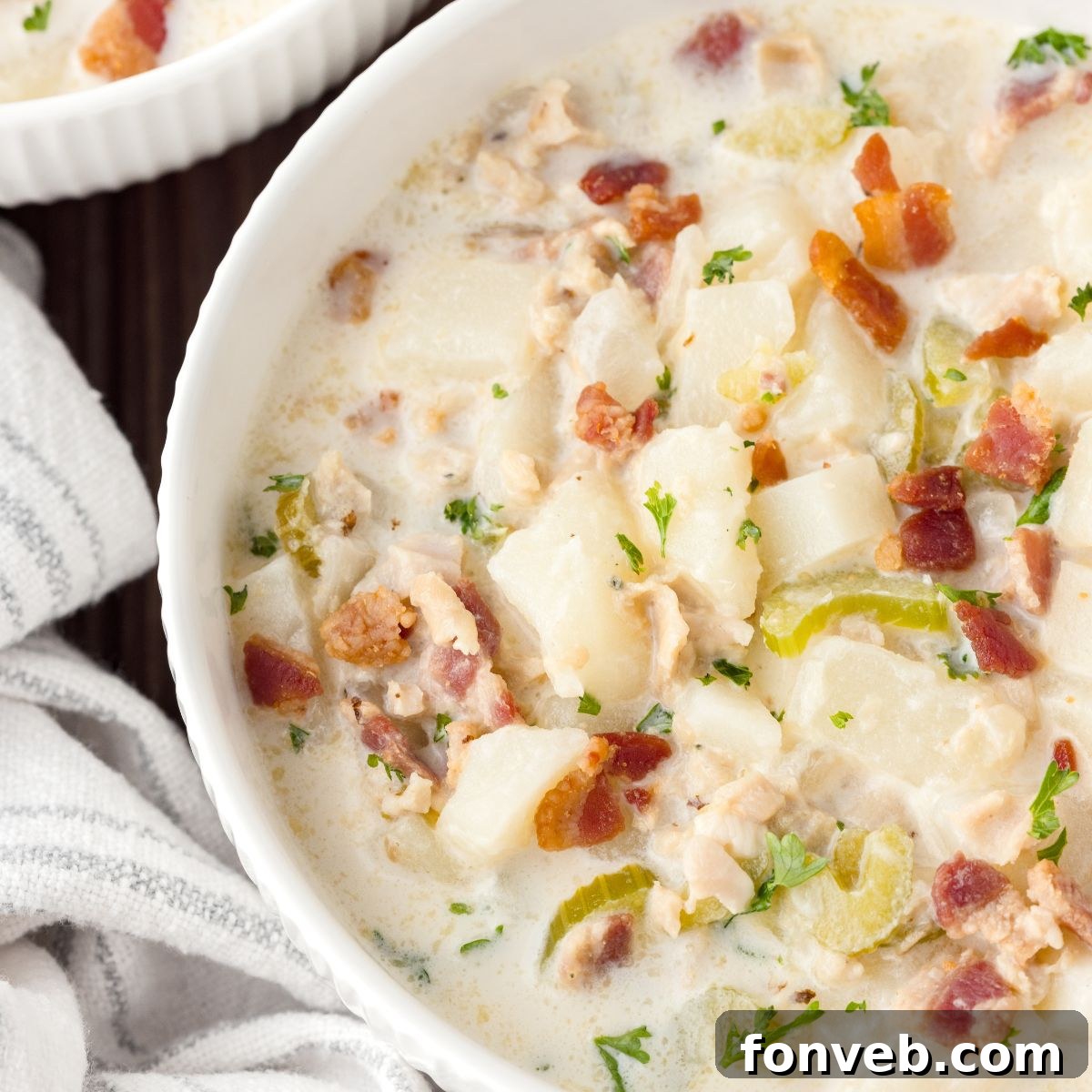 New England Clam Chowder in a bowl with a towel beside it sitting on table 