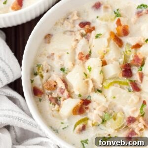 New England Clam Chowder in a bowl with a towel beside it sitting on table