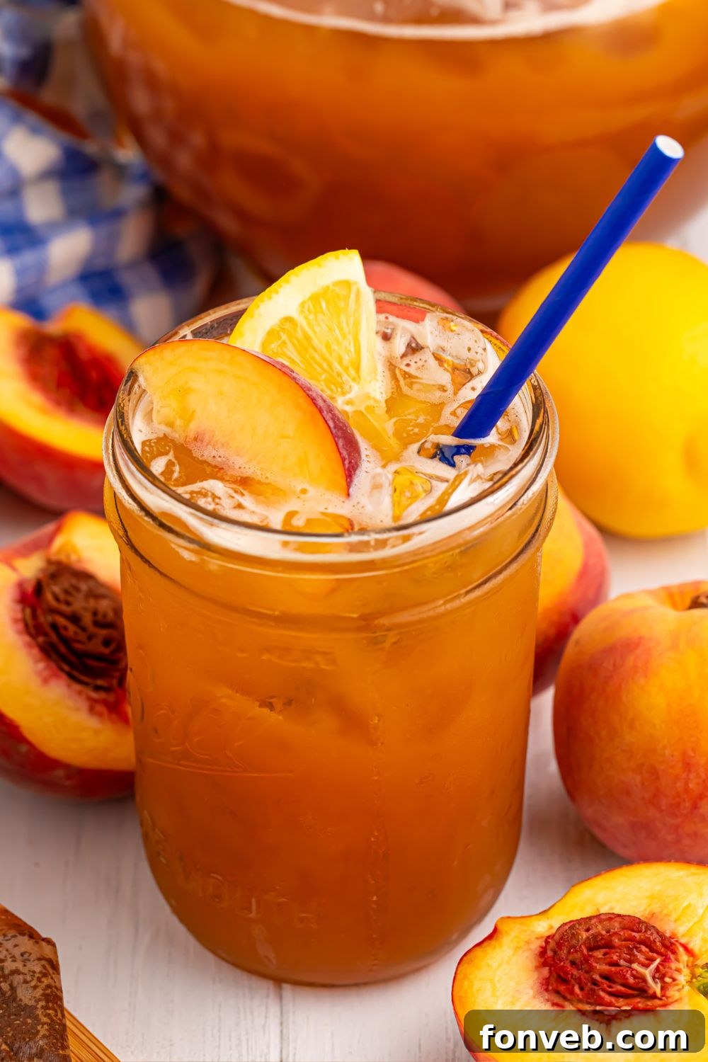glass of sweet peach tea and sliced peaches all around it on table