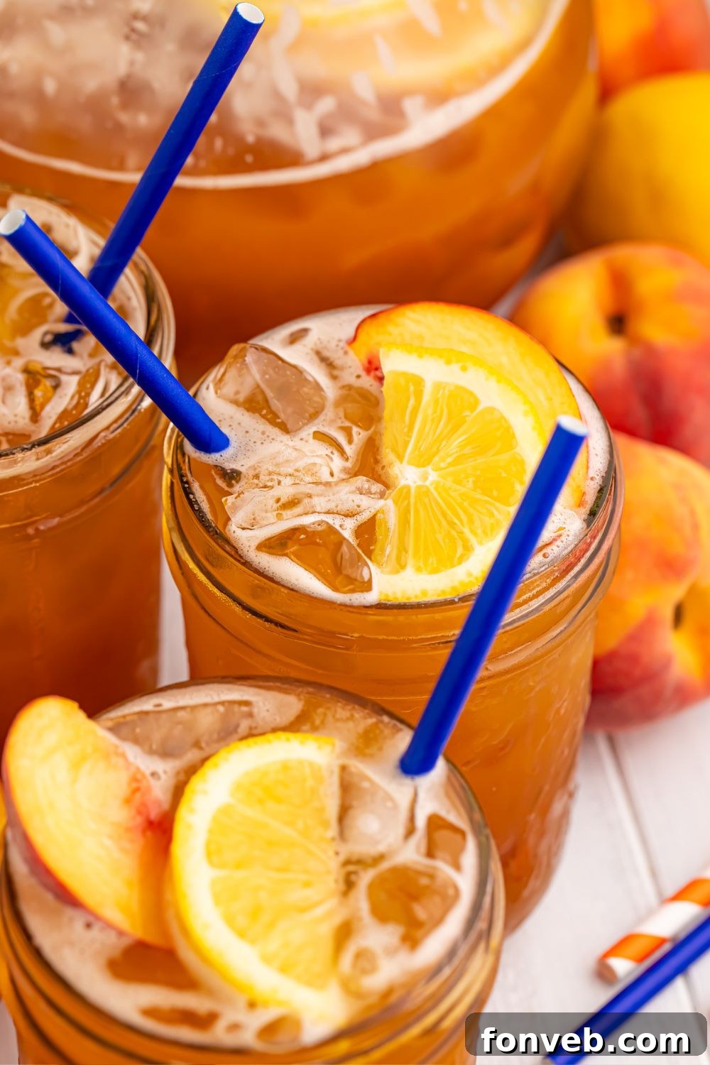 glasses of tea sitting on table with whole peaches in the background to show this is a peach tea recipe