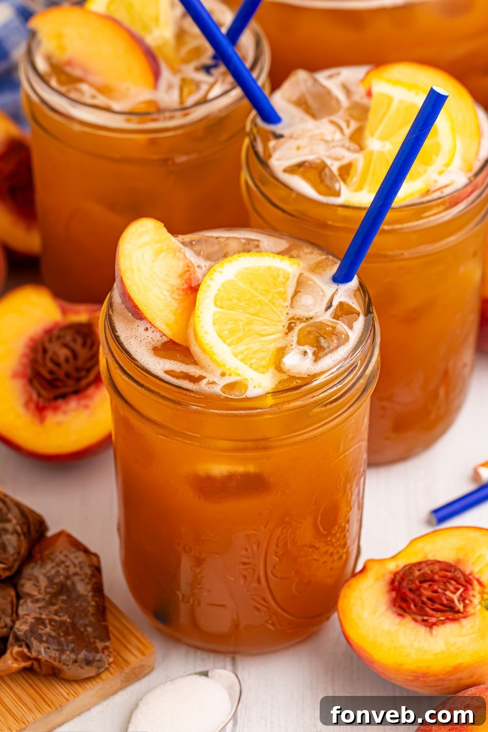 mason jars with Sweet peach tea in each glass and fresh peaches around the glasses on table