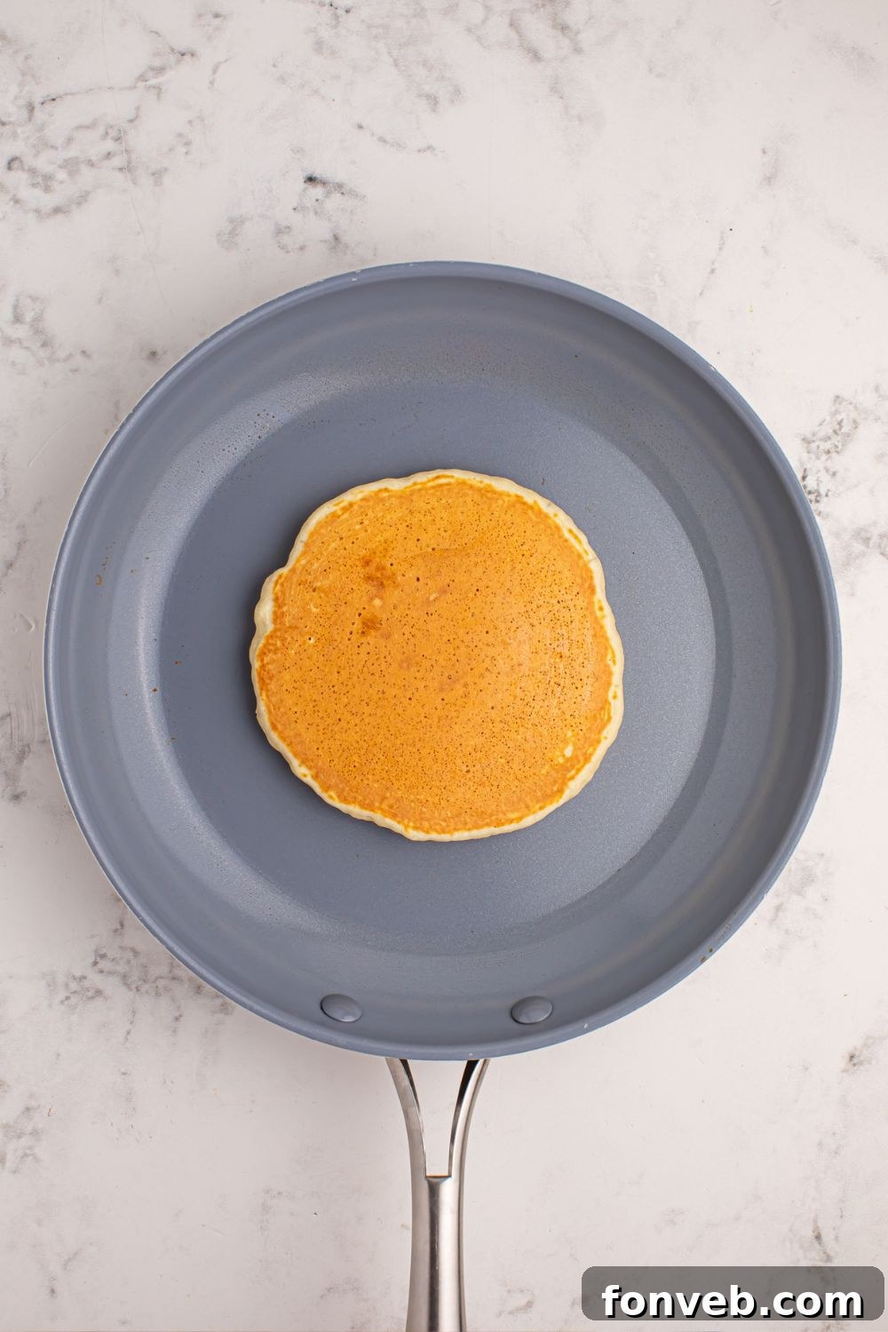 A golden-brown pancake perfectly cooked in the center of a non-stick skillet.