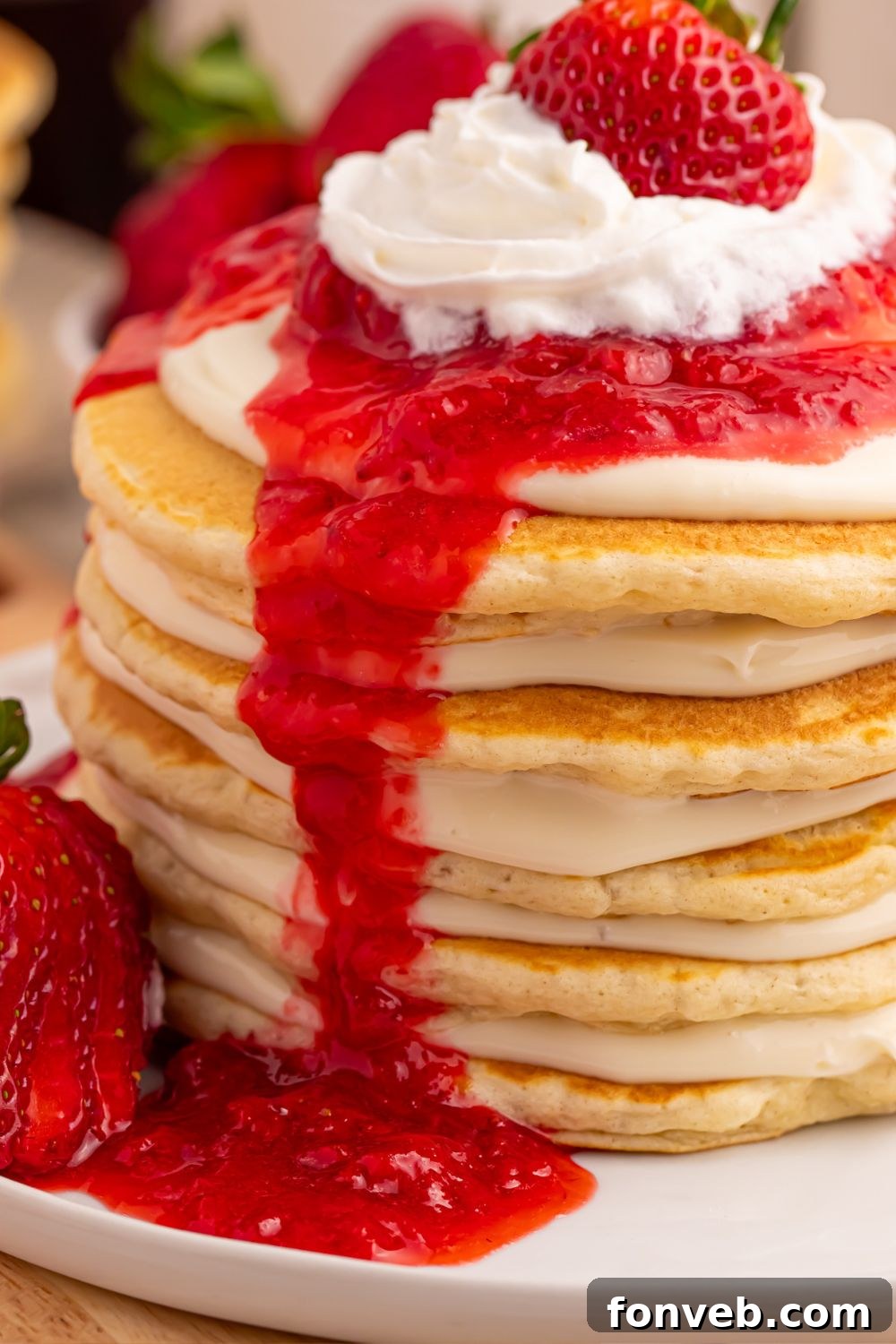 A close-up side view of a stack of Strawberry Cheesecake Pancakes, highlighting the creamy cheesecake layers between the pancakes.