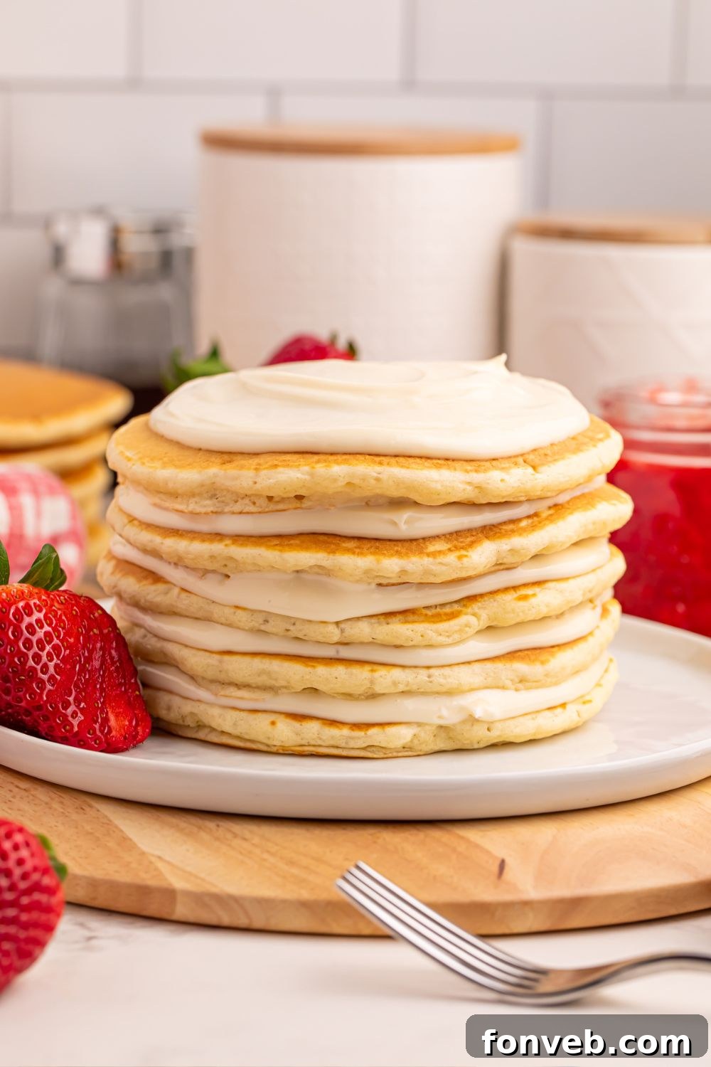 A stack of Strawberry Cheesecake Pancakes showing the cream cheese filling spread between layers on a plate.