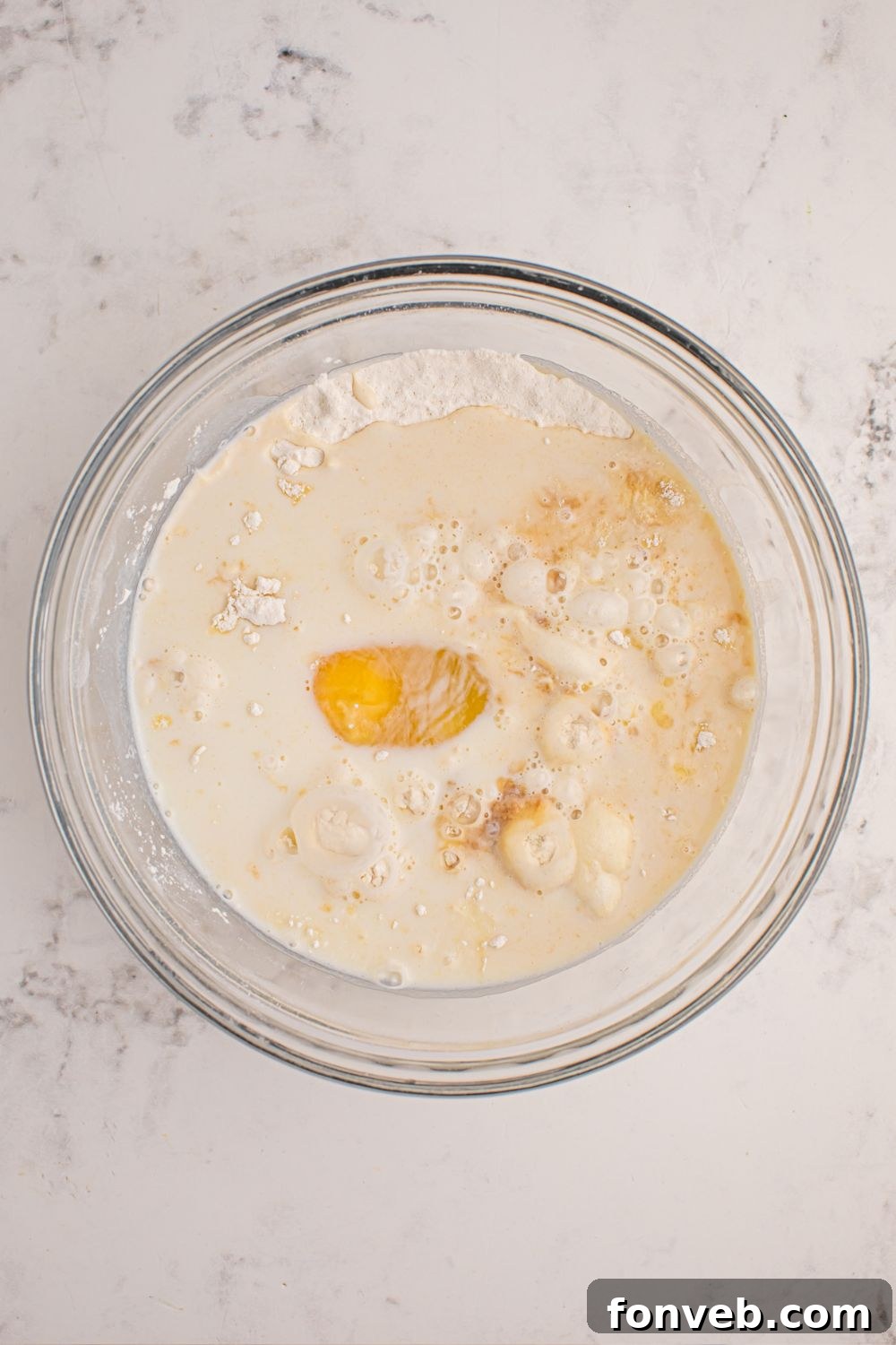 Pancake batter mixed in a clear glass bowl, showing its smooth consistency.