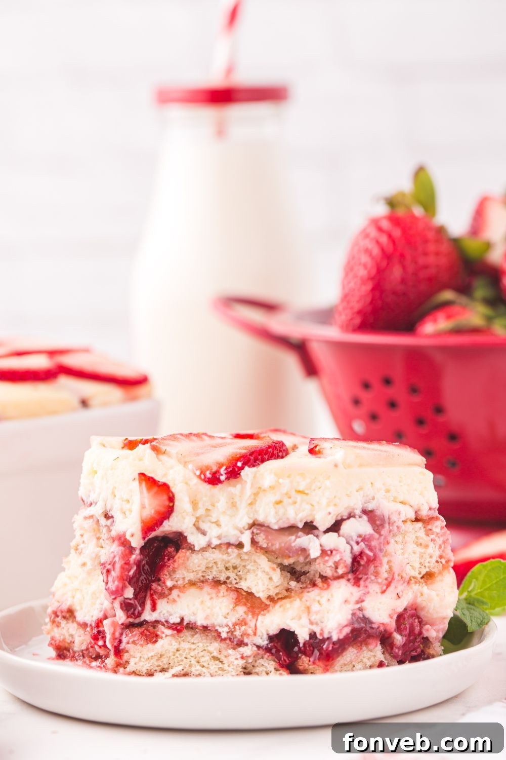 strainer of strawberries, glass of milk, and plate with tiramisu