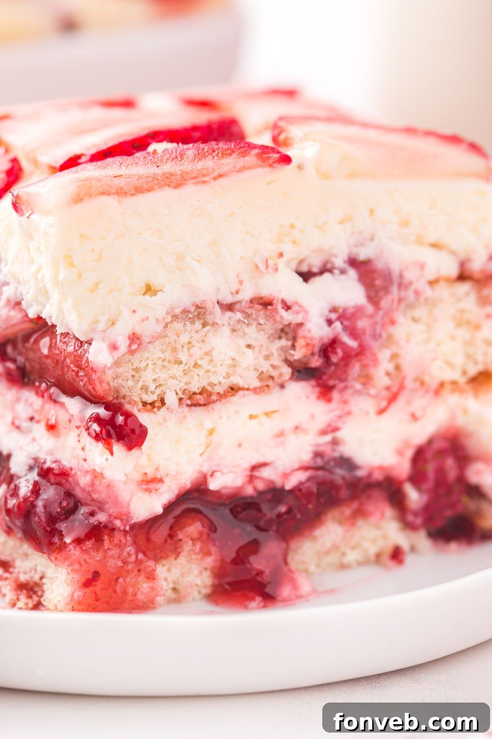 Strawberry Tiramisu sliced on a plate with a glass of milk behind it 