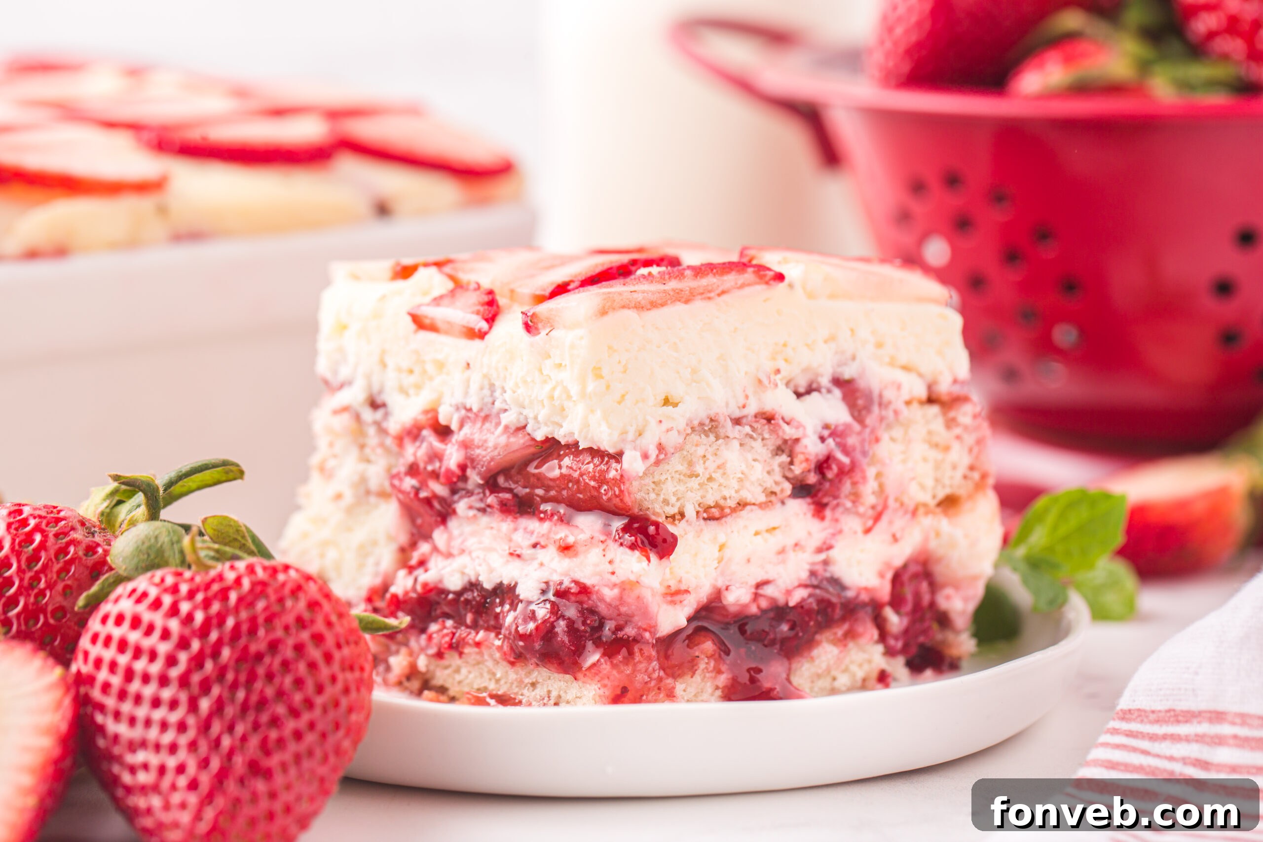 side view of Strawberry Tiramisu on a white plate surrounded by fresh strawberries