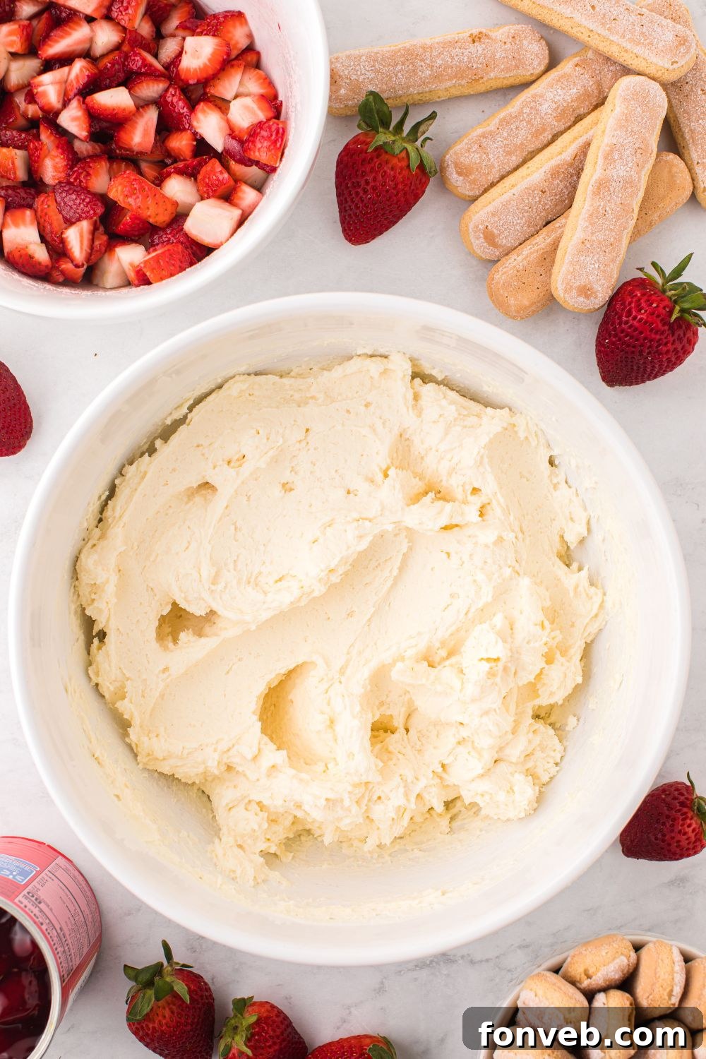 mascarpone filling on table in a bowl with ladyfingers and berries in bowls 