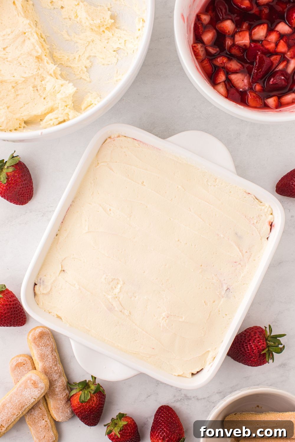 Strawberry Tiramisu being made and bowl of strawberries on side