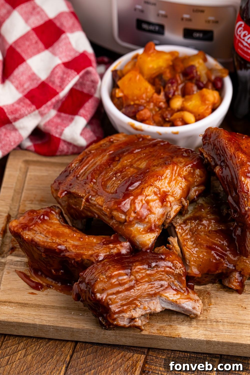 Slow Cooker Coca Cola Ribs served on a wooden table alongside a bowl of BBQ baked beans