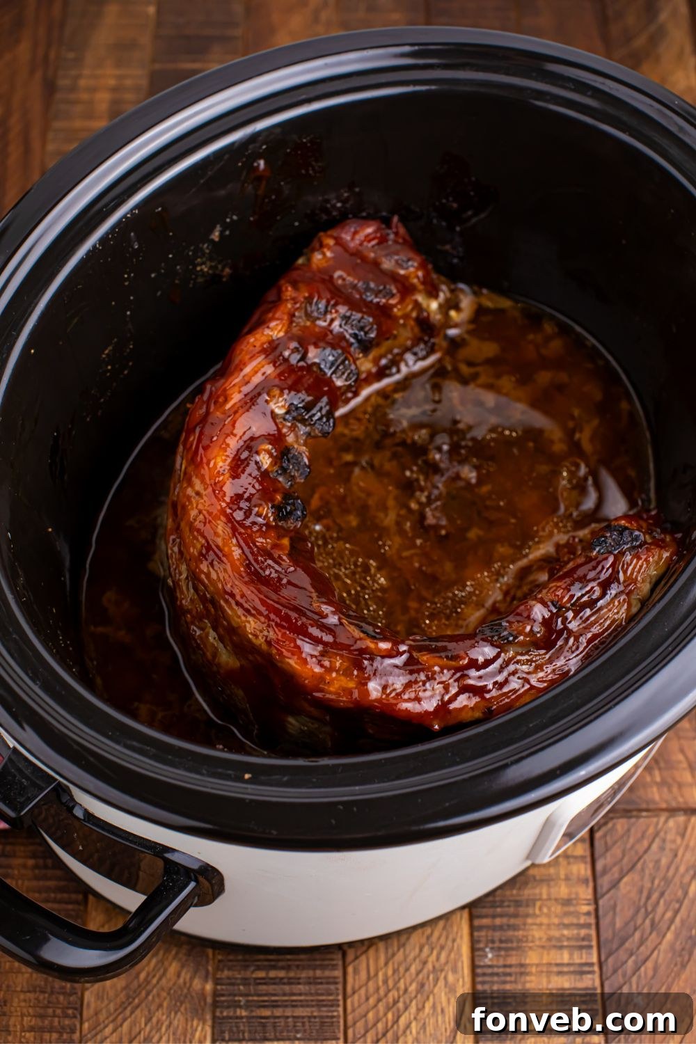 Slow cooker filled with perfectly cooked Coca Cola ribs, ready to be served