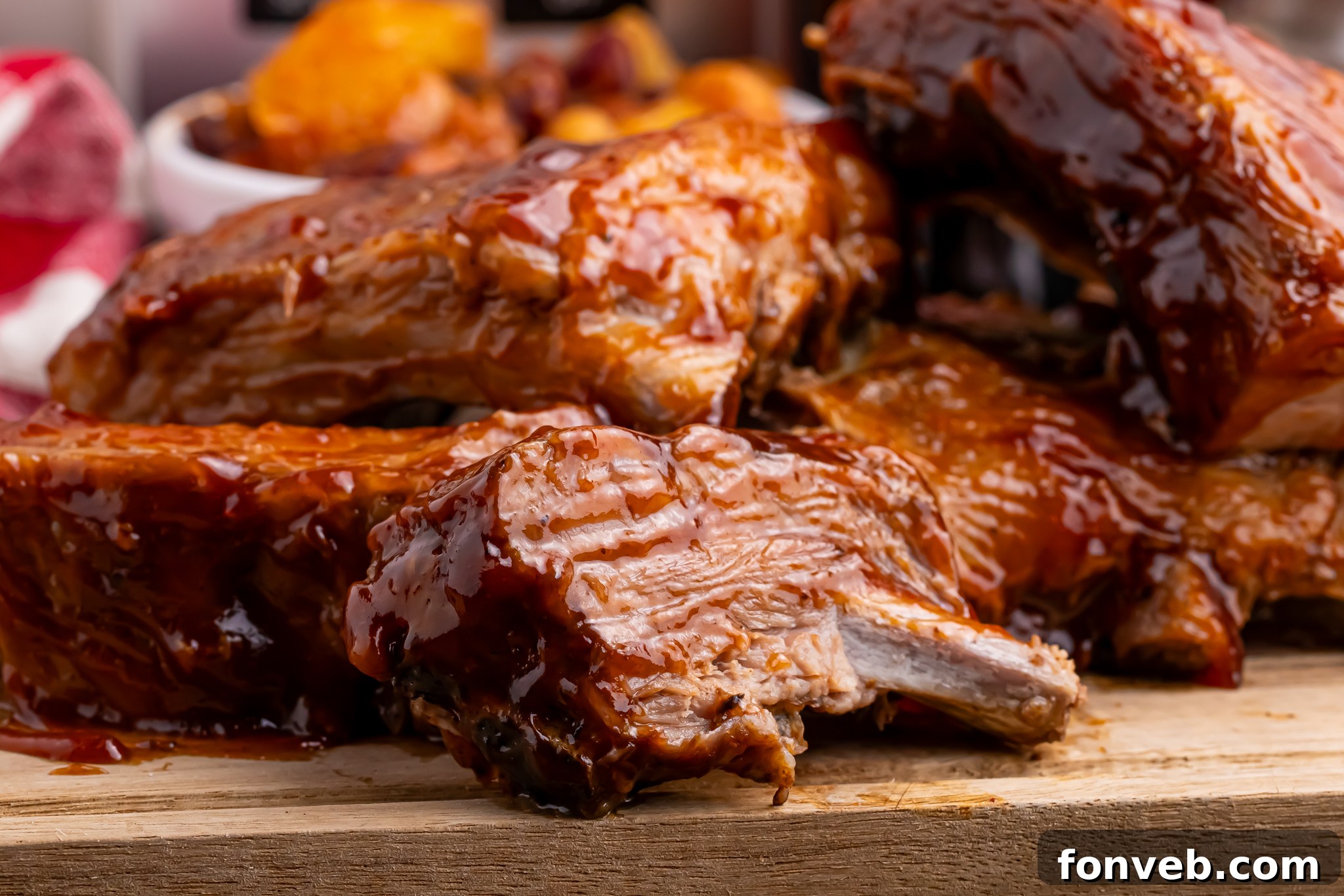 A large platter of cooked Coca Cola ribs on a wooden cutting board, glistening with sauce