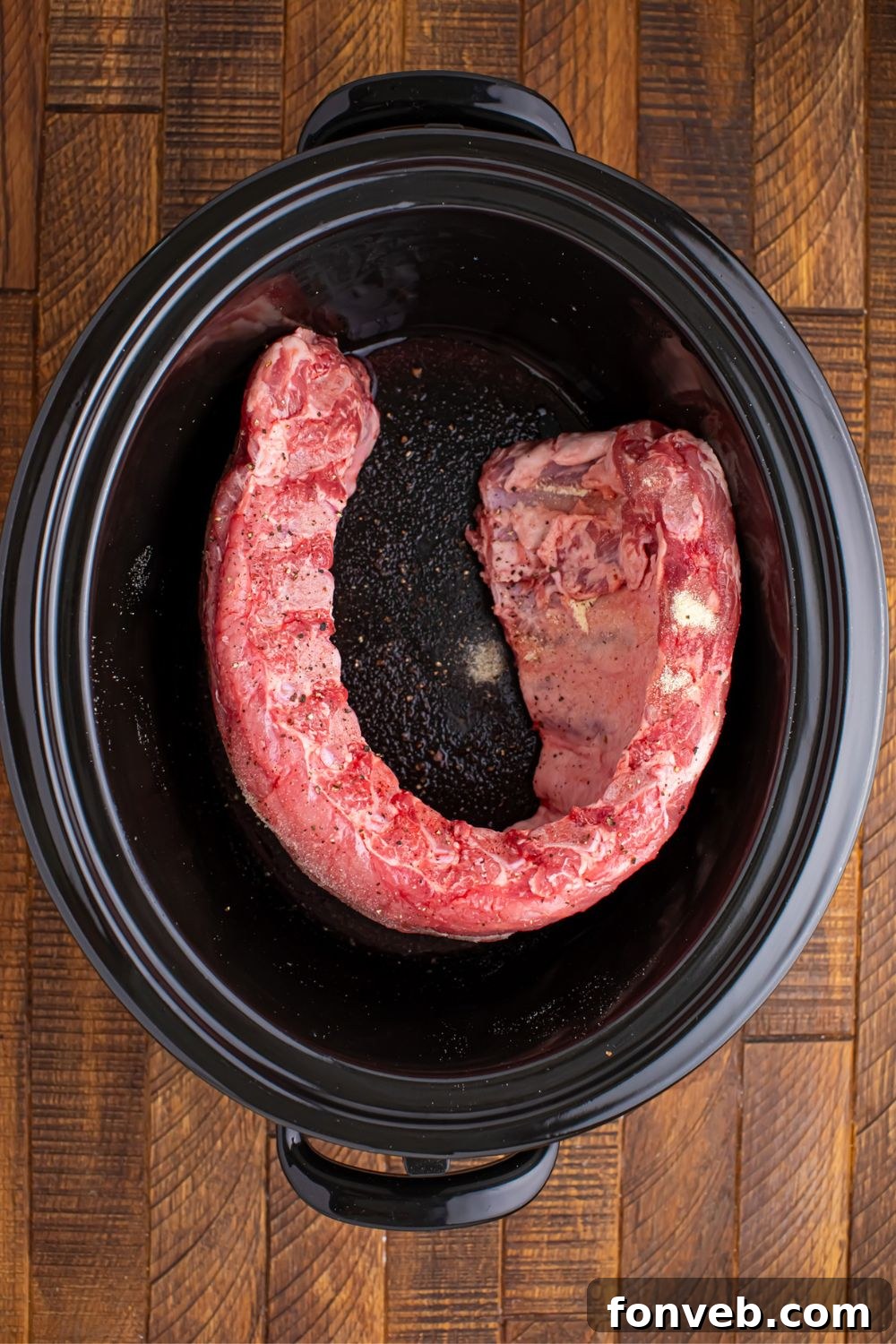 Raw baby back ribs perfectly placed in a slow cooker, ready for seasoning