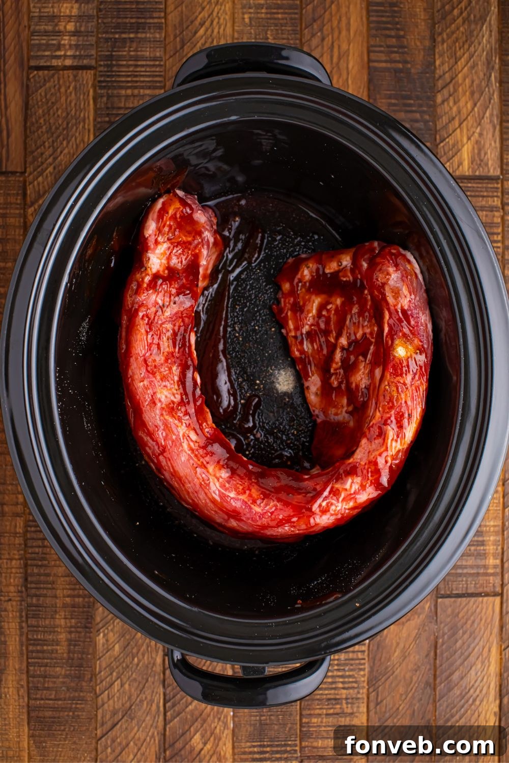 Baby back ribs seasoned and basted with BBQ sauce in a slow cooker