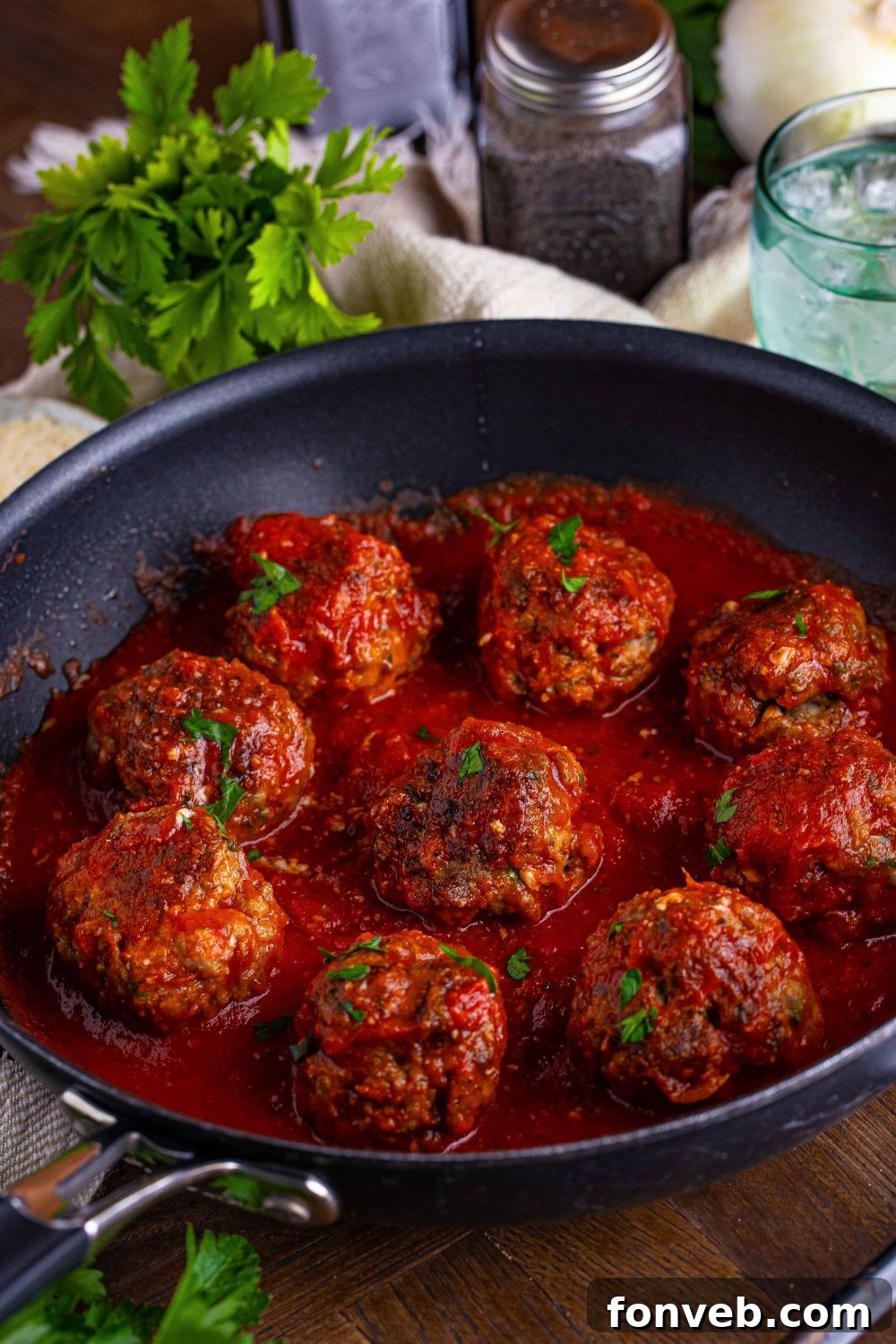 Italian Meatballs in a pan with parsley and salt and pepper in the background 