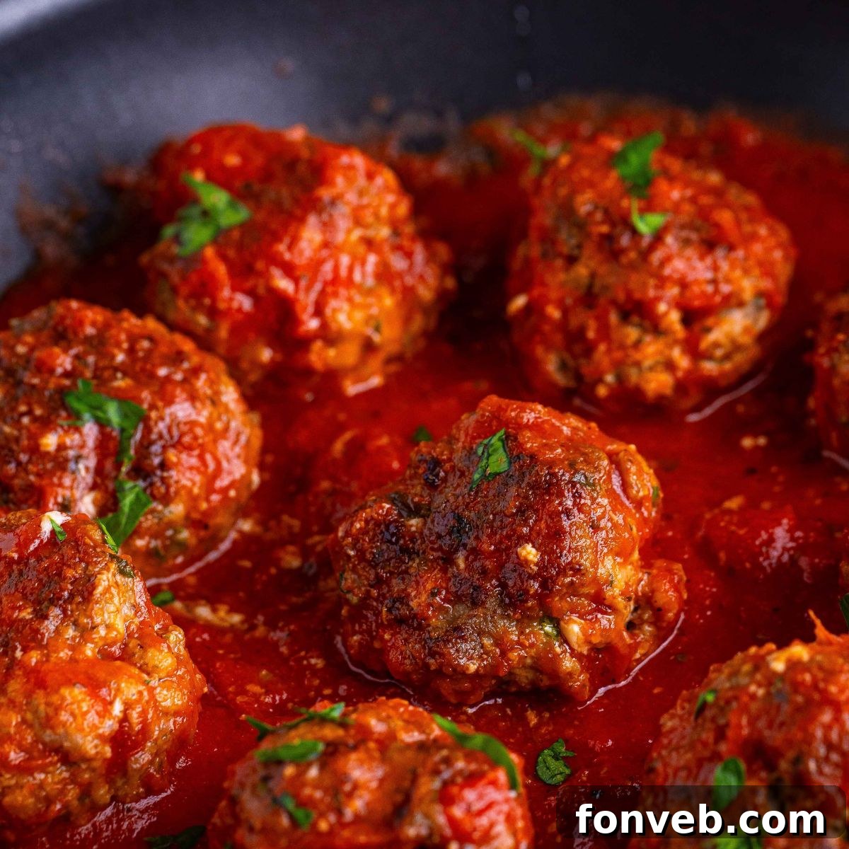 Classic Italian Meatballs in a pan with some sauce over the top of the meatballs 