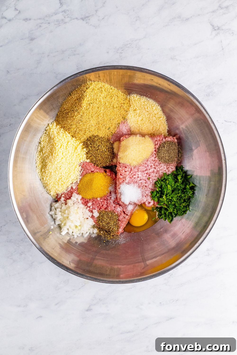 ingredients for the meatballs in a metal bowl on table 