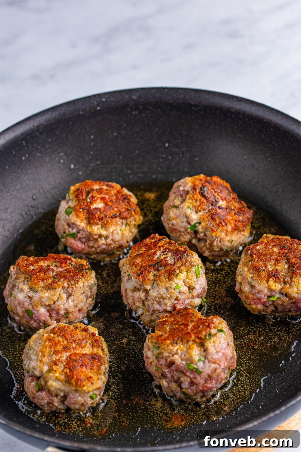 Classic Italian Meatballs being seared in a skillet 