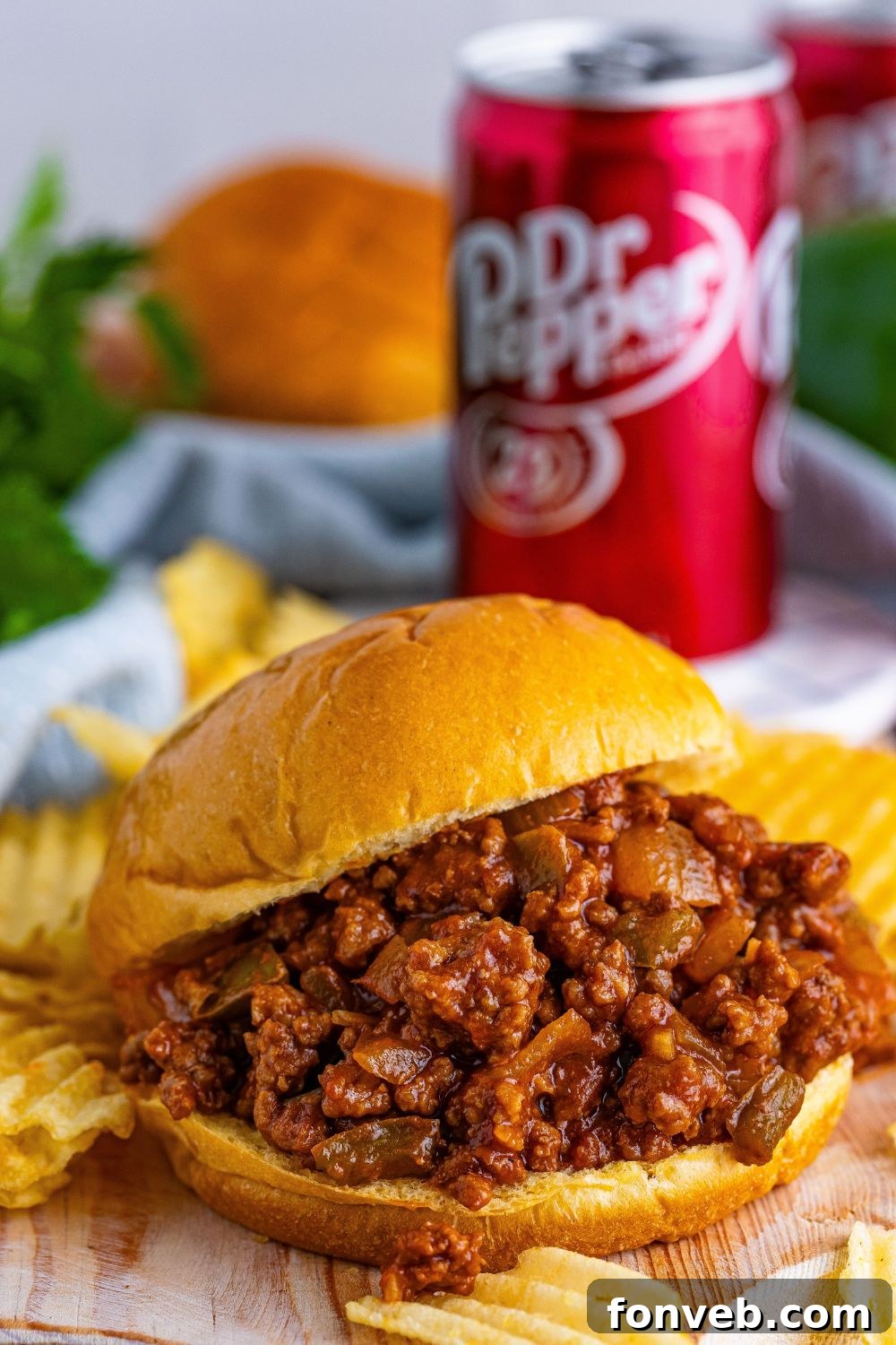 Dr. Pepper Sloppy Joes sitting on cutting board with a pile of chips around the cutting board 