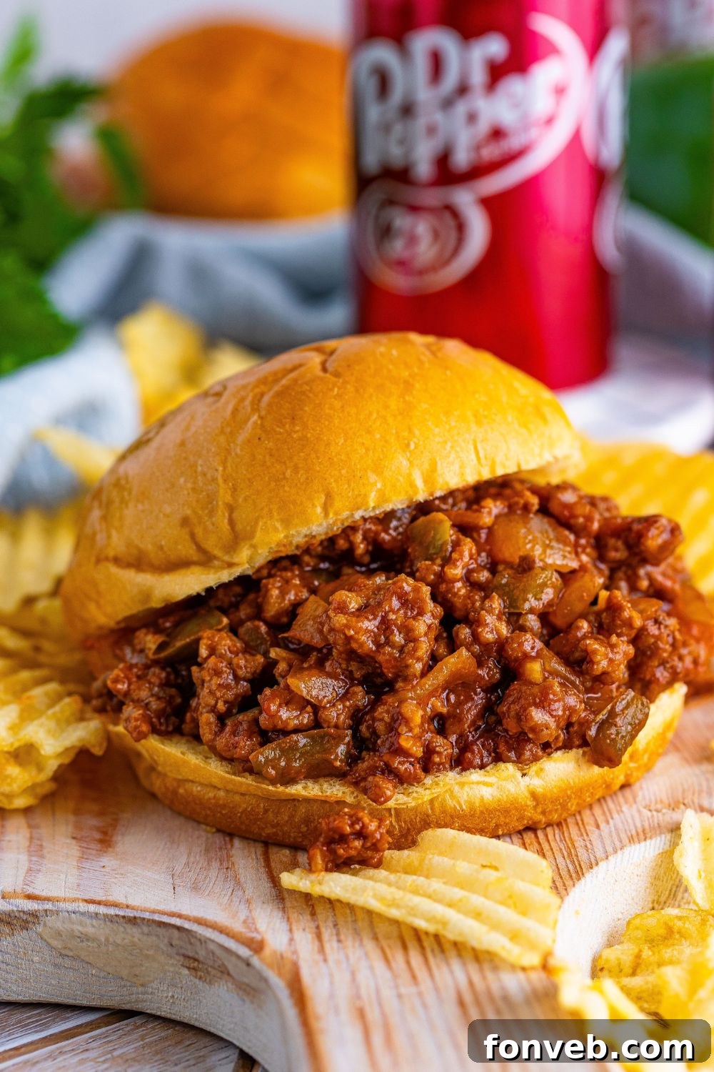 Dr. Pepper Sloppy Joe sandwich sitting on a cutting board with soda in the background