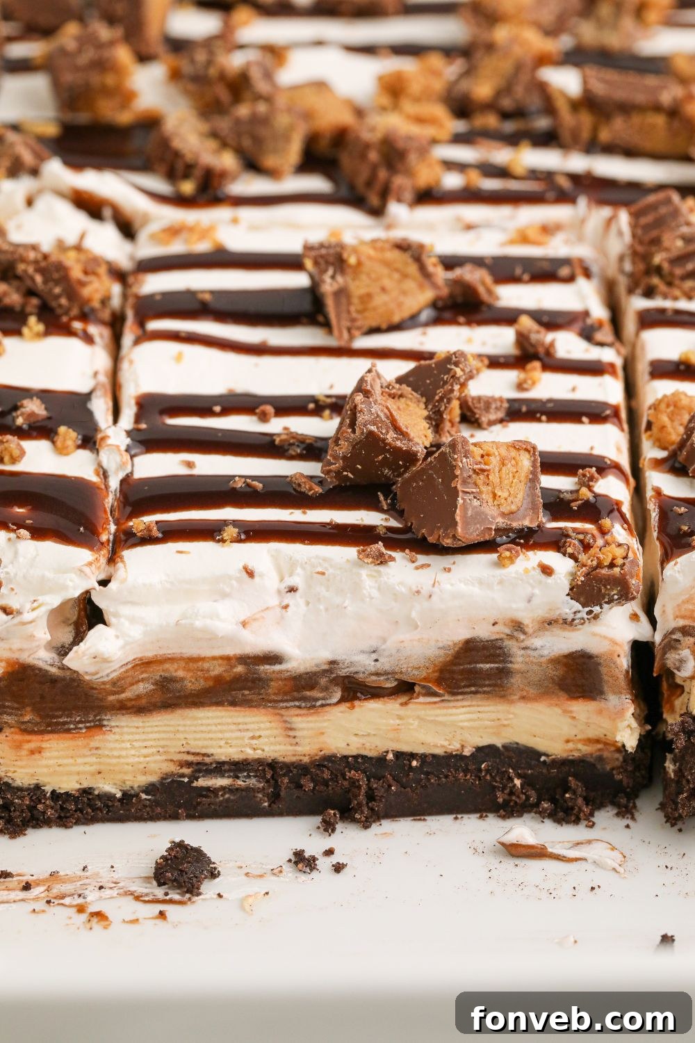 Peanut Butter Chocolate Sweet Stack 19 Reeses Lasagna in a white casserole pan with a few slices taken out of pan