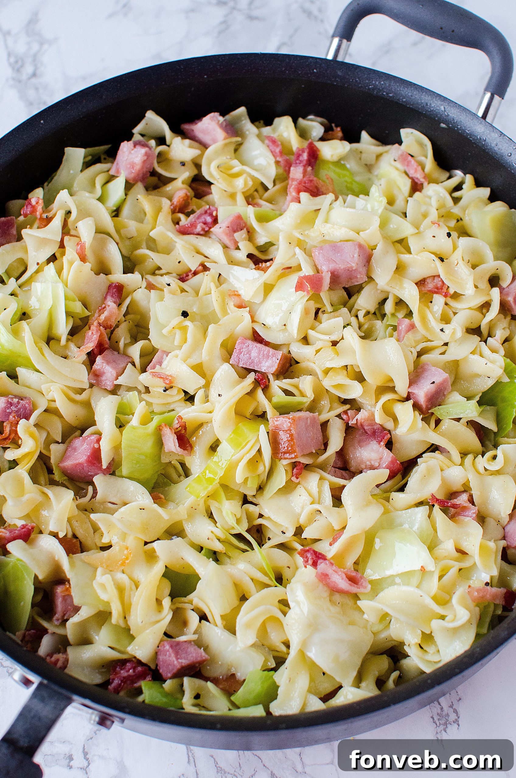 Hearty Haluski dish with fried cabbage, ham, and noodles served in a bowl, ready to eat.